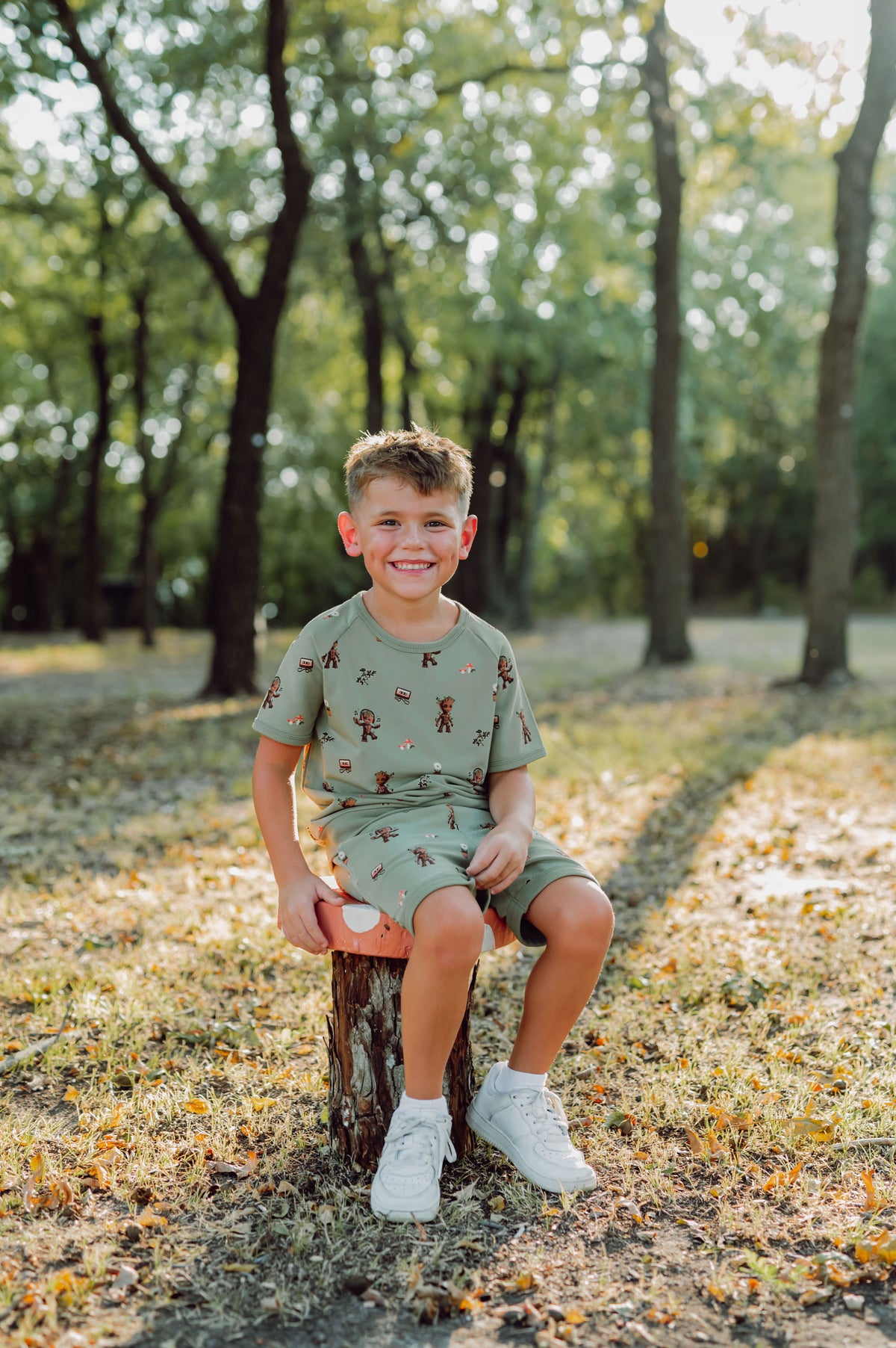 Boy outside sitting on a tree stump in groot short sleeve jogger set.
