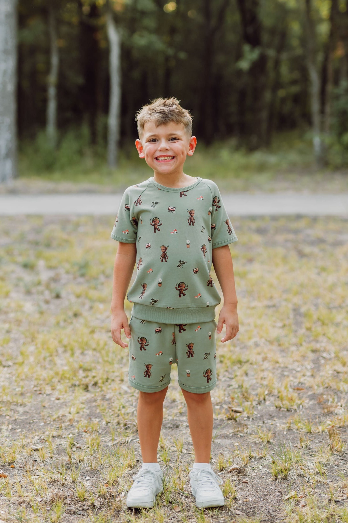 Boy outside smiling wearing groot shorts sleeve jogger set.
