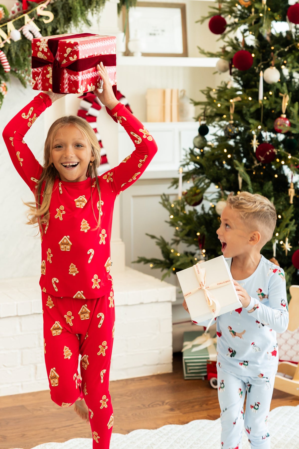 2 kids running with christmas presents in kyte baby christmas pajamas