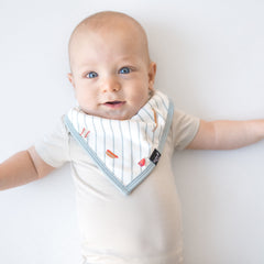 Young baby wearing the Bib in Home Run overtop a light cream short sleeve bodysuit