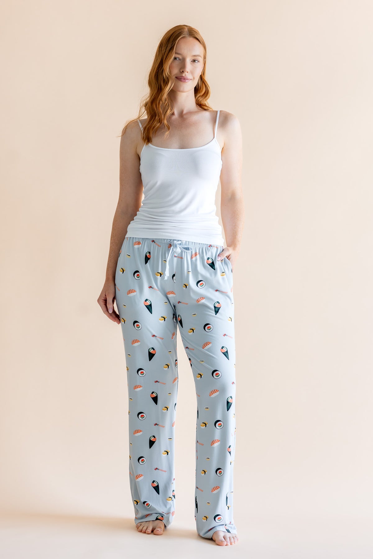 Model in blue Women's Lounge Pants in Sushi print under white camisole on a beige background