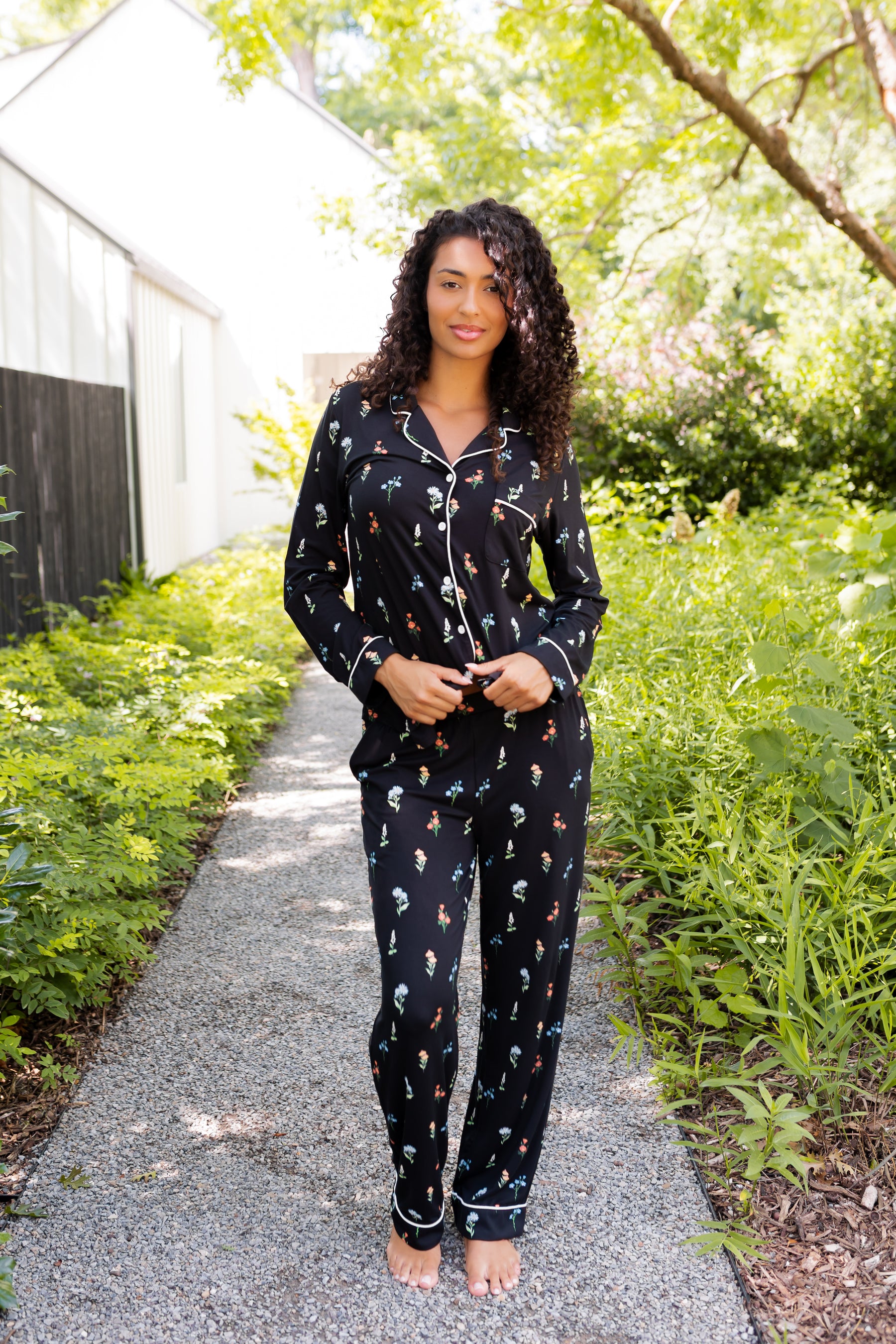 Model wearing Long-Sleeved Women's Pajama Set in Midnight Wildflower print standing outdoors surrounded by trees