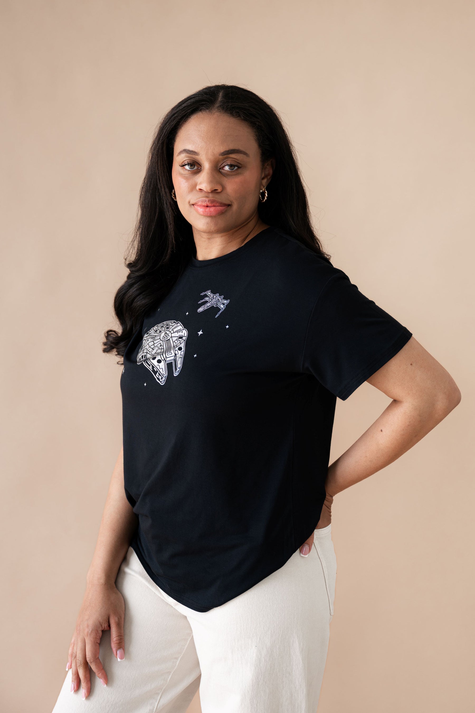 Female standing with one hand on her hip wearing the Women's Graphic Tee in Millennium Falcon™