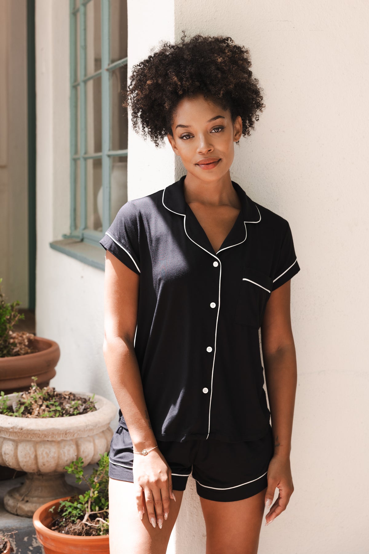 Female modeling the Women’s Short Sleeve Pajama Set in Midnight with Cloud Trim leaning against a white wall
---1615 1