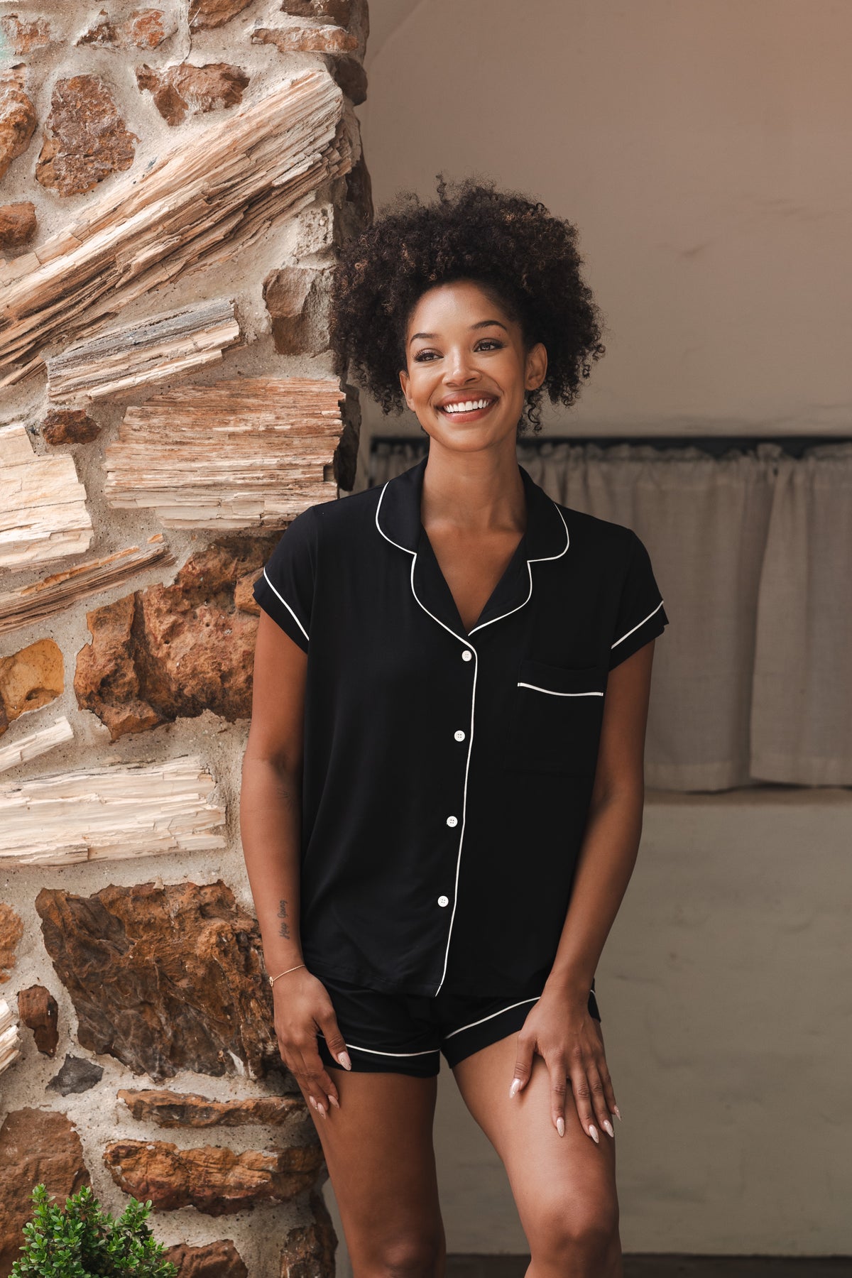 Smiling female wearing the Women’s Short Sleeve Pajama Set in Midnight with Cloud Trim at the entrance of a house