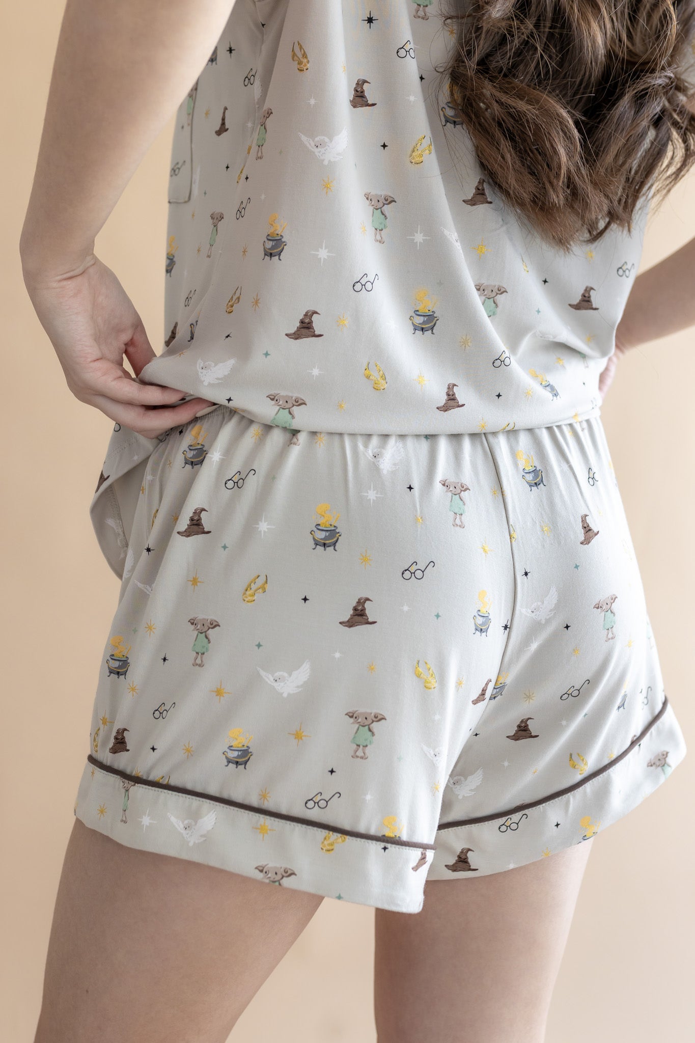 Back side of a model wearing Women's Short Sleeve Pajama Set Shorts with Harry Potter prints on a beige background