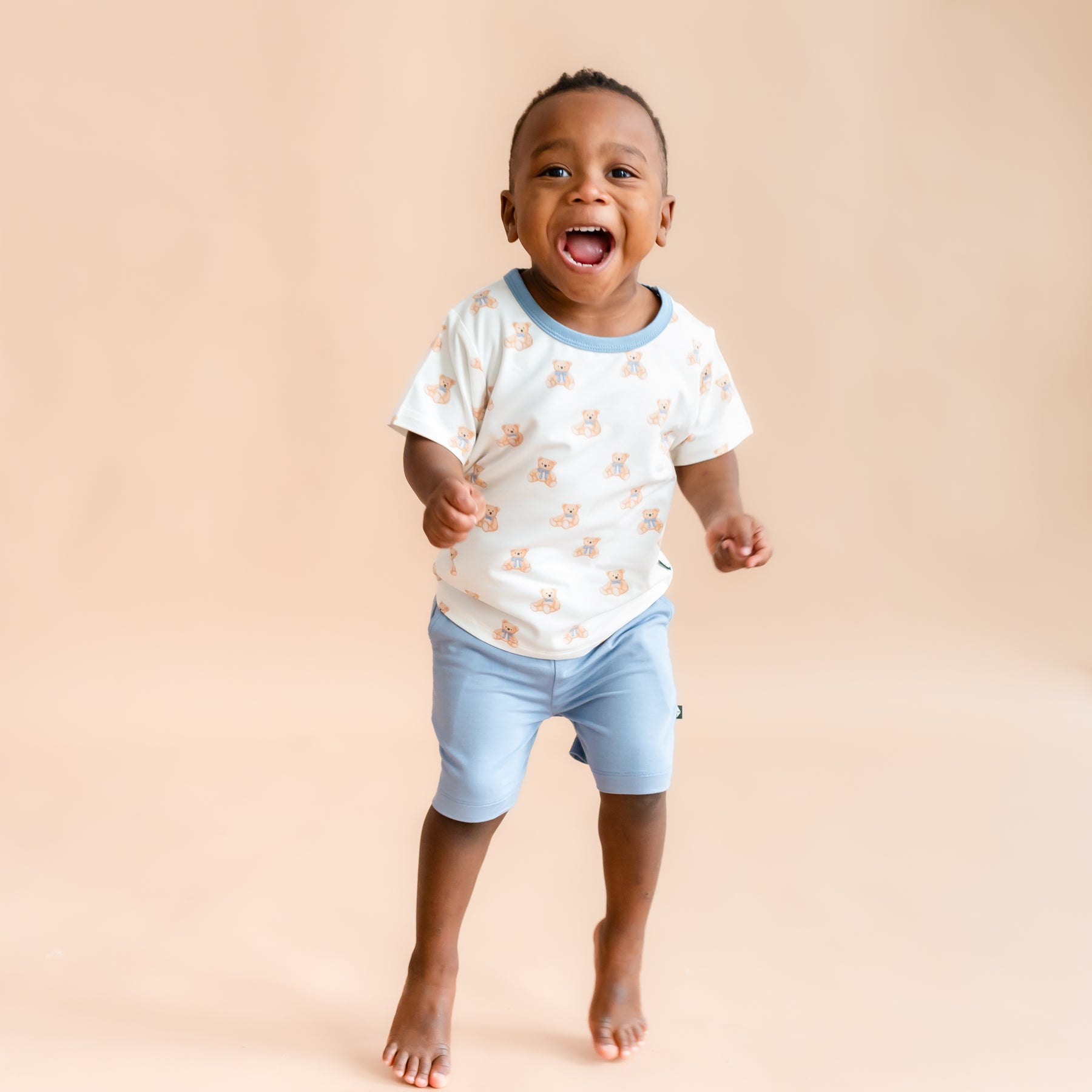 toddler boy jumping and smiling wearing  Toddler Basic Tee in Teddy Bear