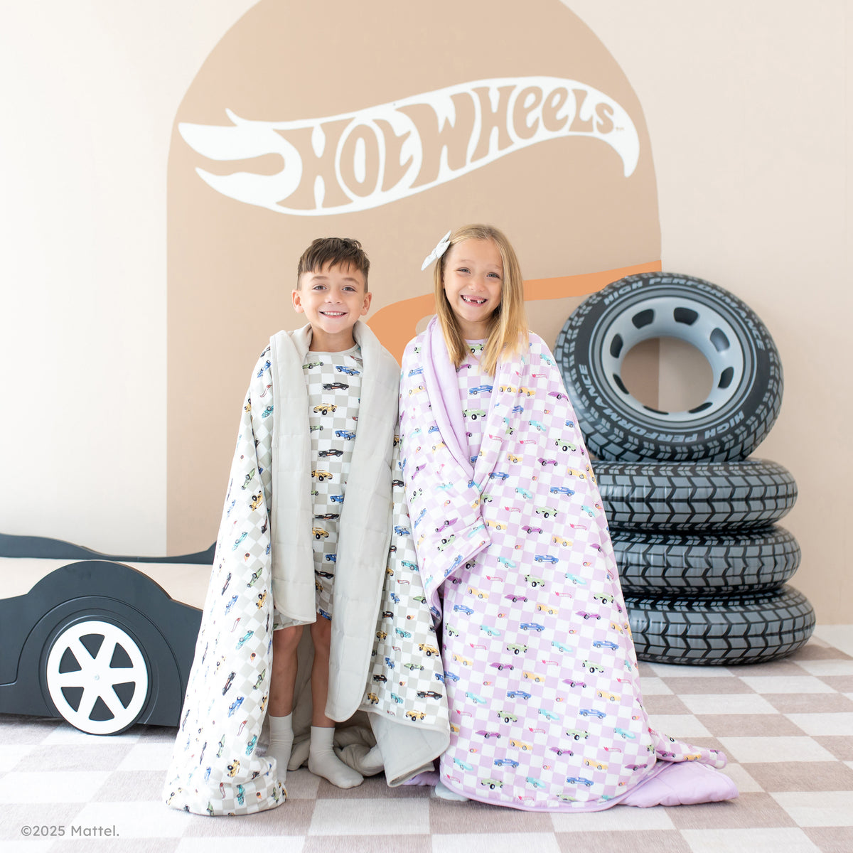 2 children in Hot Wheels x Kyte collab pajamas and blankets
