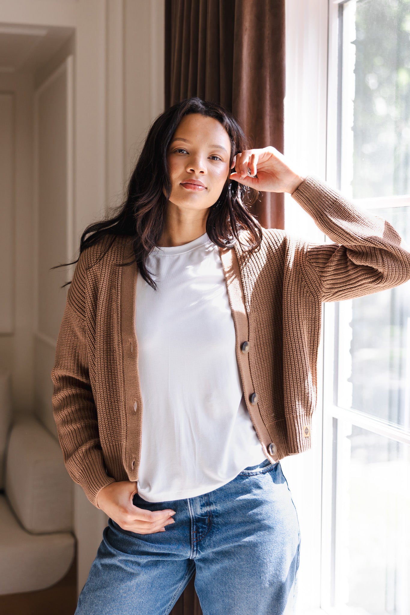 Modal posing in Chunky Knit Women's Cropped Cardigan in Latte over white T-shirt and blue jeans