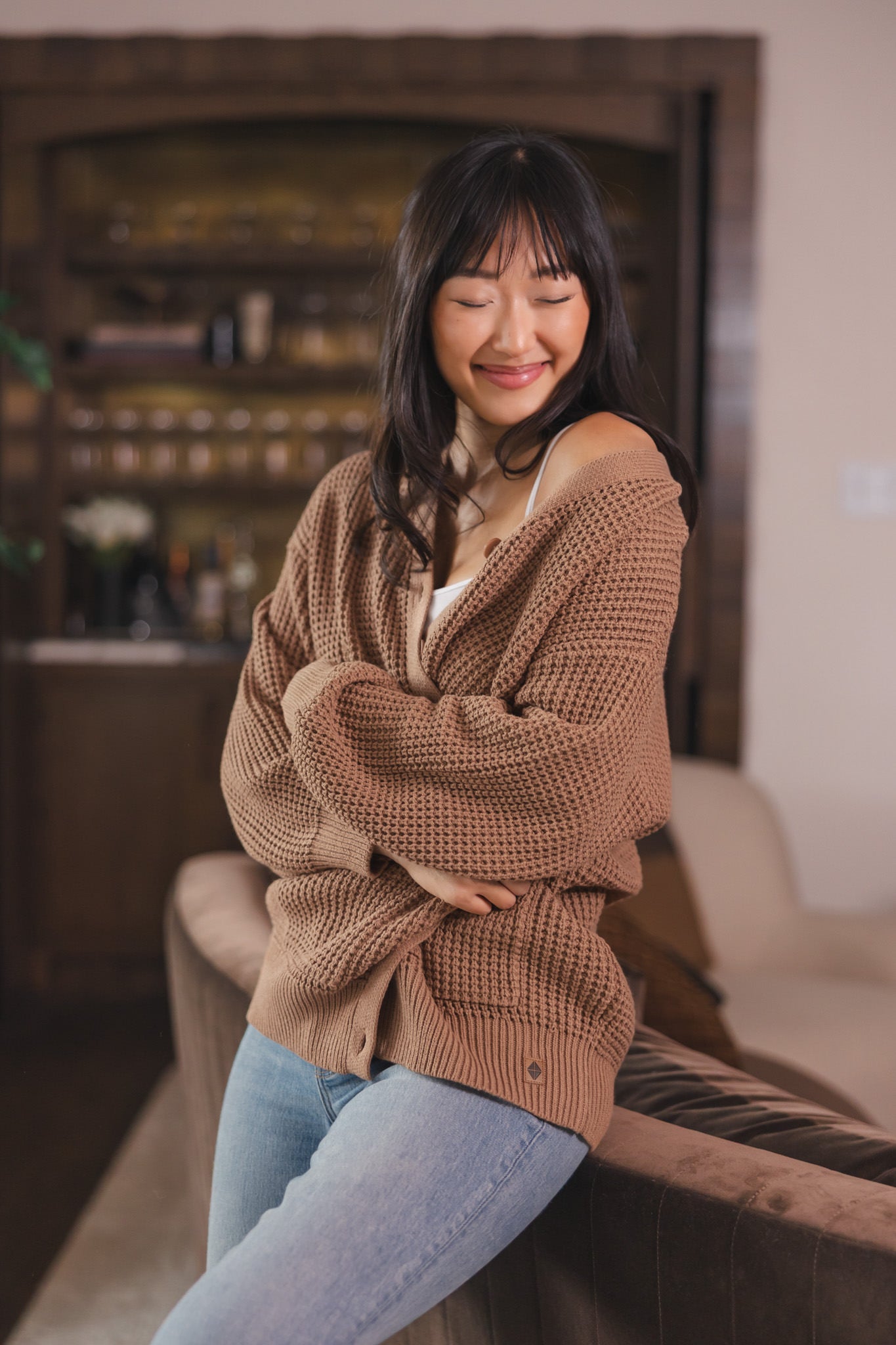 Modal posing in Chunky Knit Women's Waffle Cardigan in Latte over white camisole and blue jeans