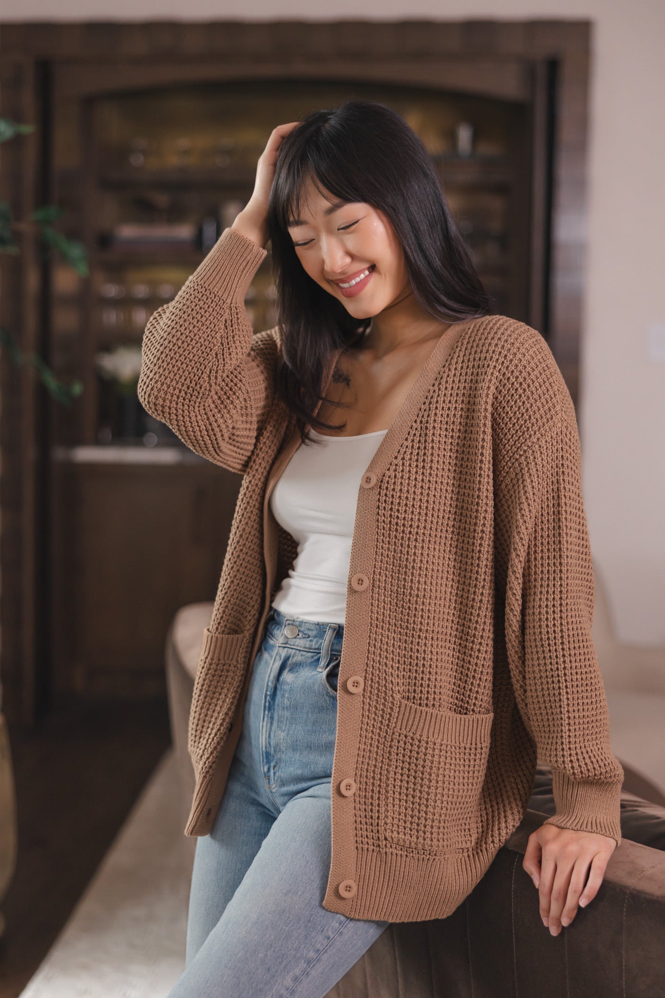 Modal smiling in Chunky Knit Women's Waffle Cardigan in Latte over white camisole and blue jeans
