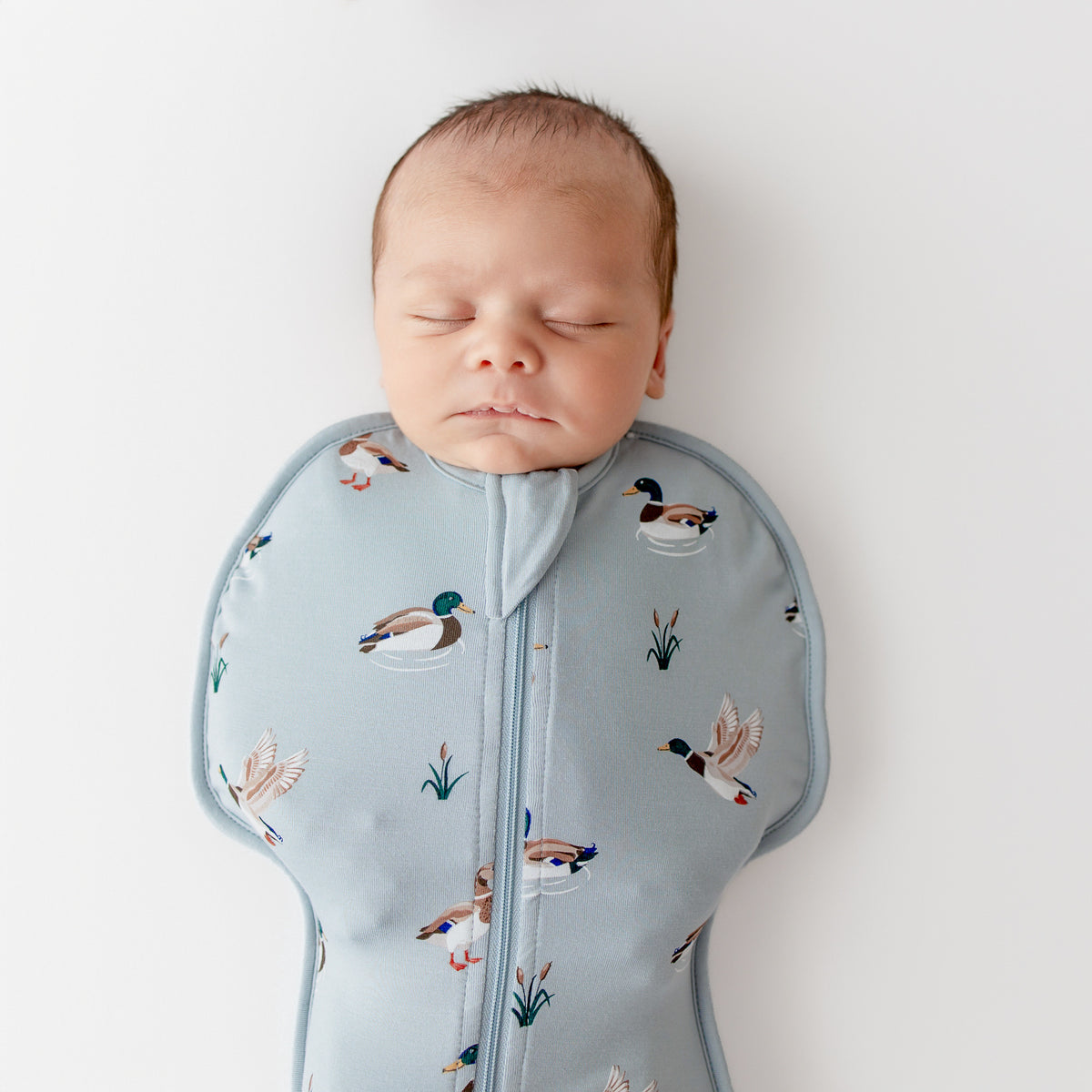 Close up of sleeping newborn wearing the Swaddle Bag in Mallard 