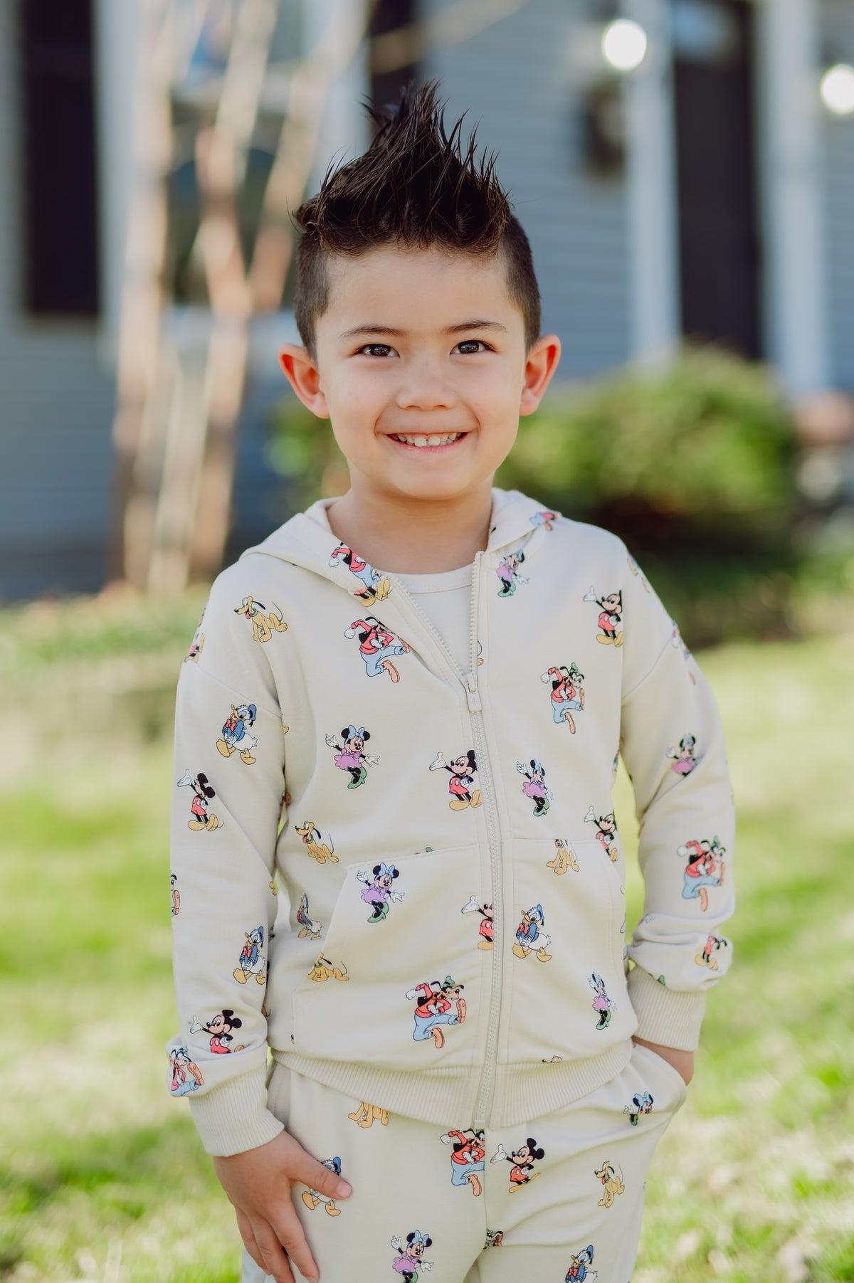 Child wearing a mickey and friends patterned hoodie and pants outdoors