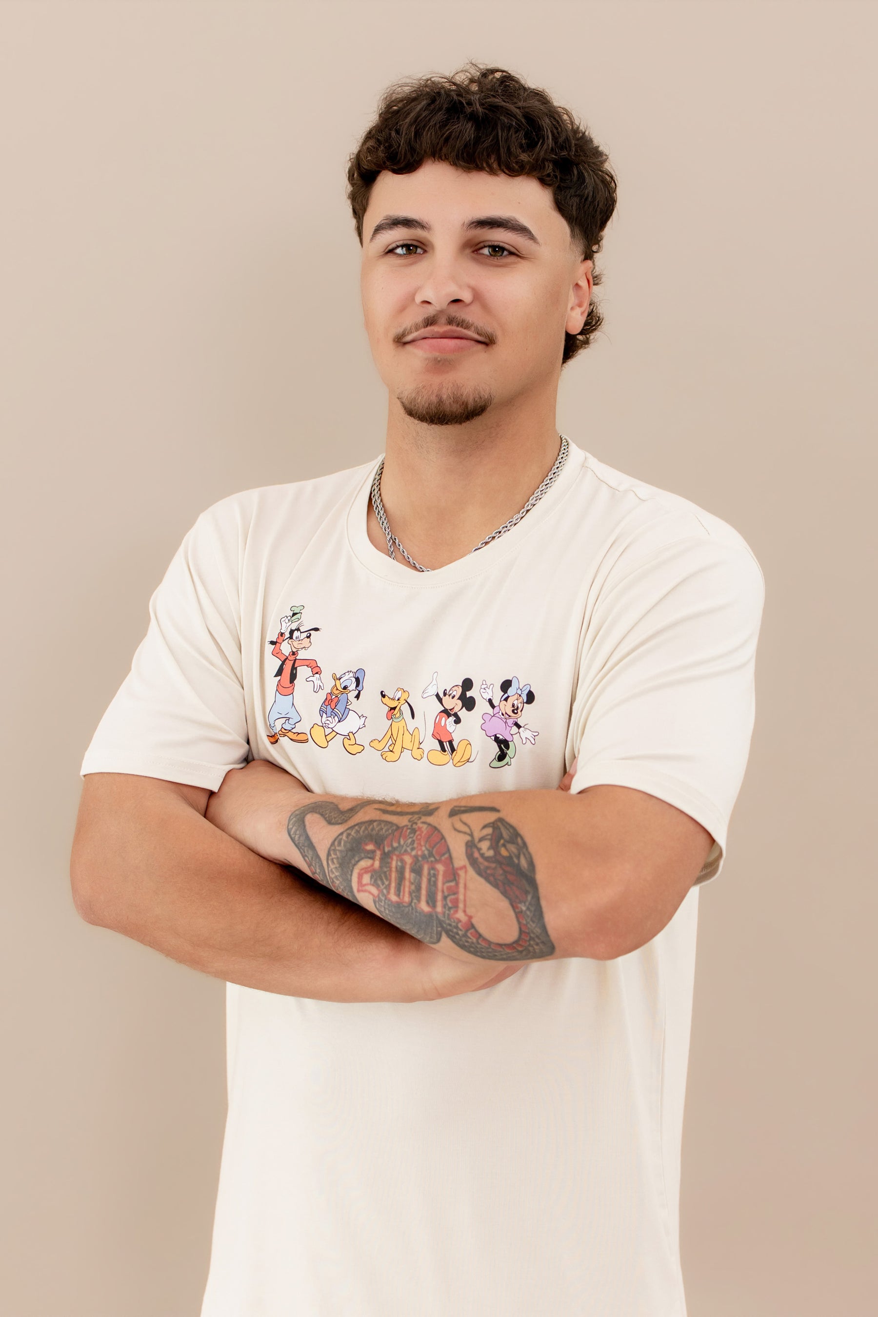 Man wearing a white t-shirt with cartoon character design against a beige background
