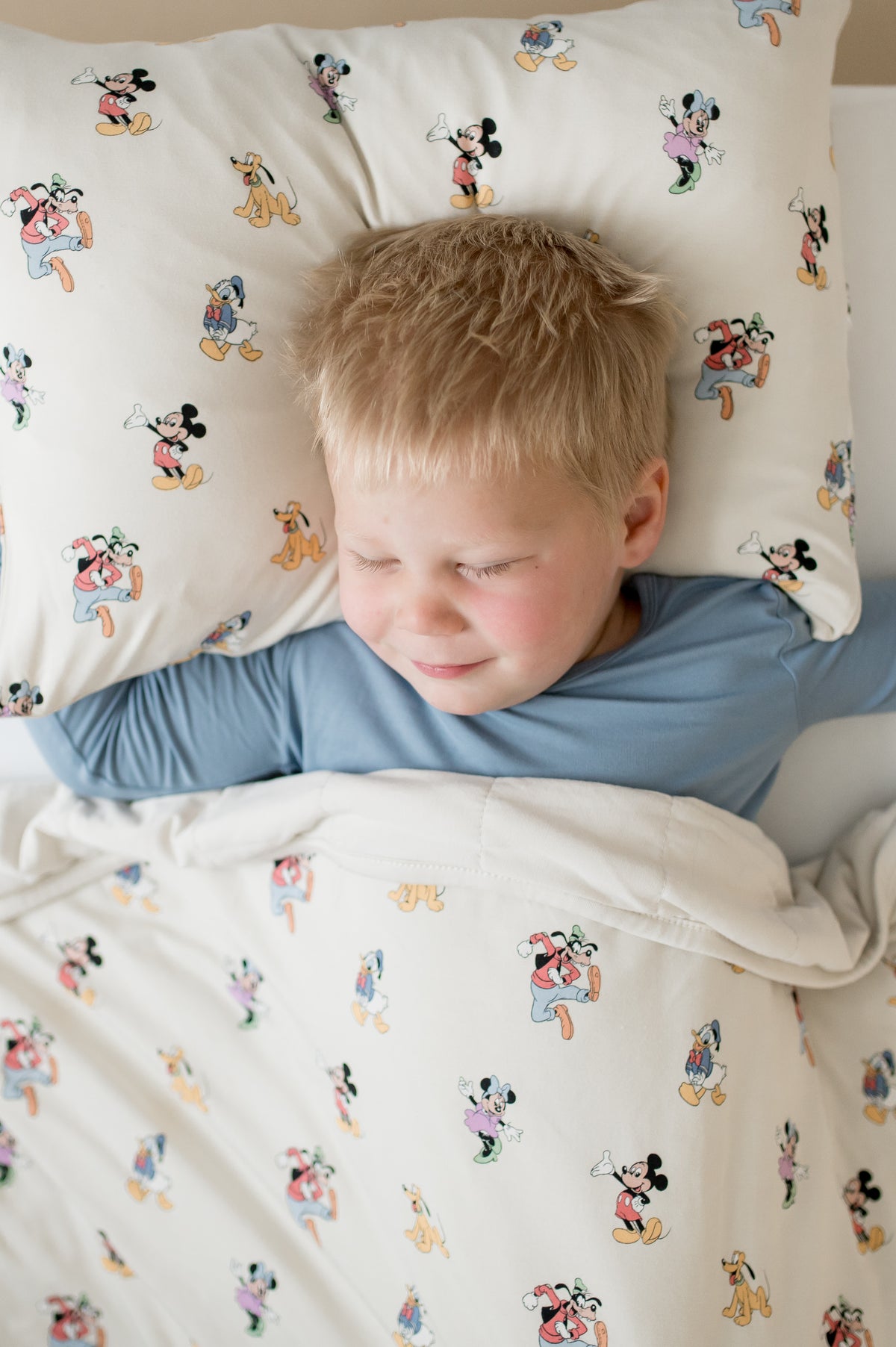 Child lying in bed with cartoon-themed bedding and pillow