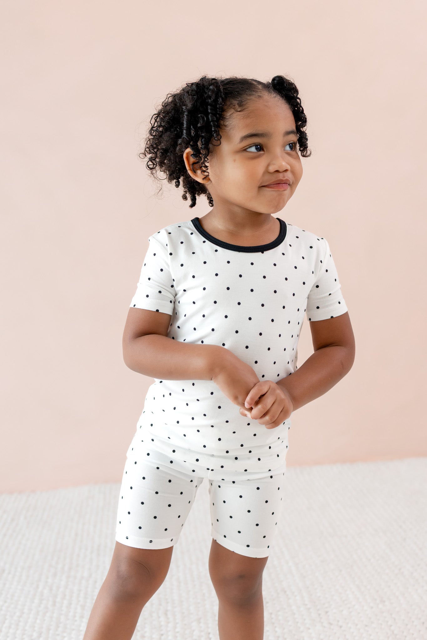 Child wearing Toddler Short Sleeve pajama set in Midnight Polka Dot print on a beige background