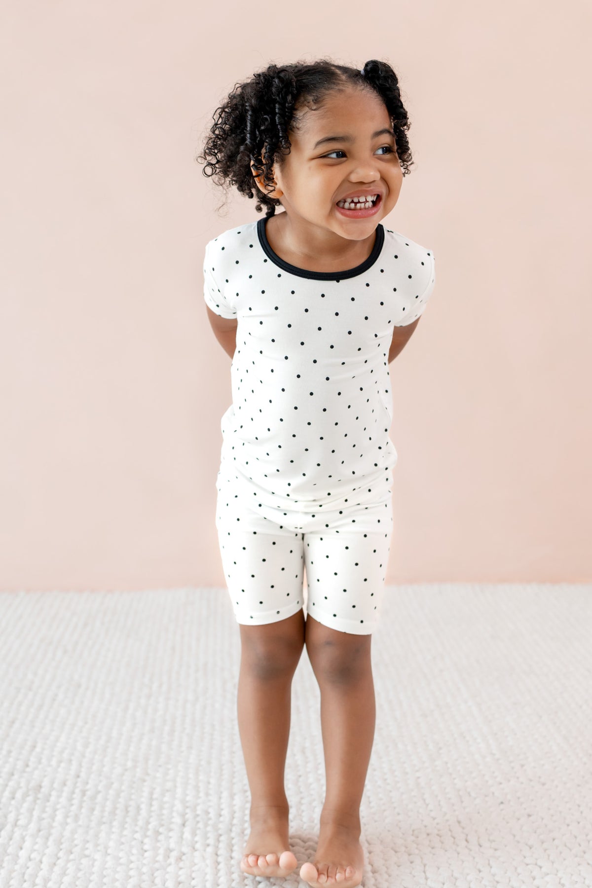 Child wearing Midnight Polka Dot print Toddler Short Sleeve pajama set on a beige background