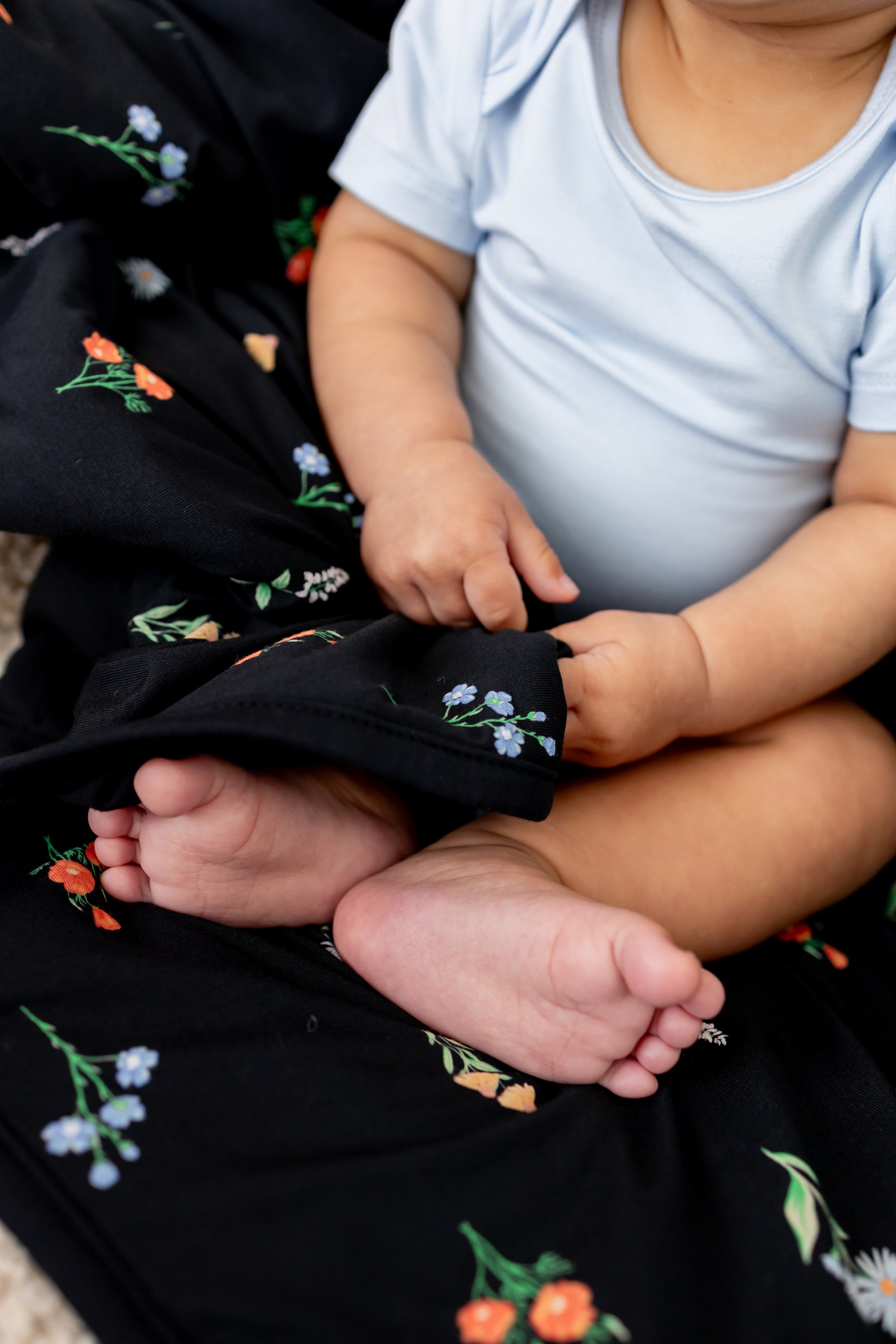 Baby sitting with Baby Blanket in Midnight Wildflower 1.0 print wearing a blue bodysuit