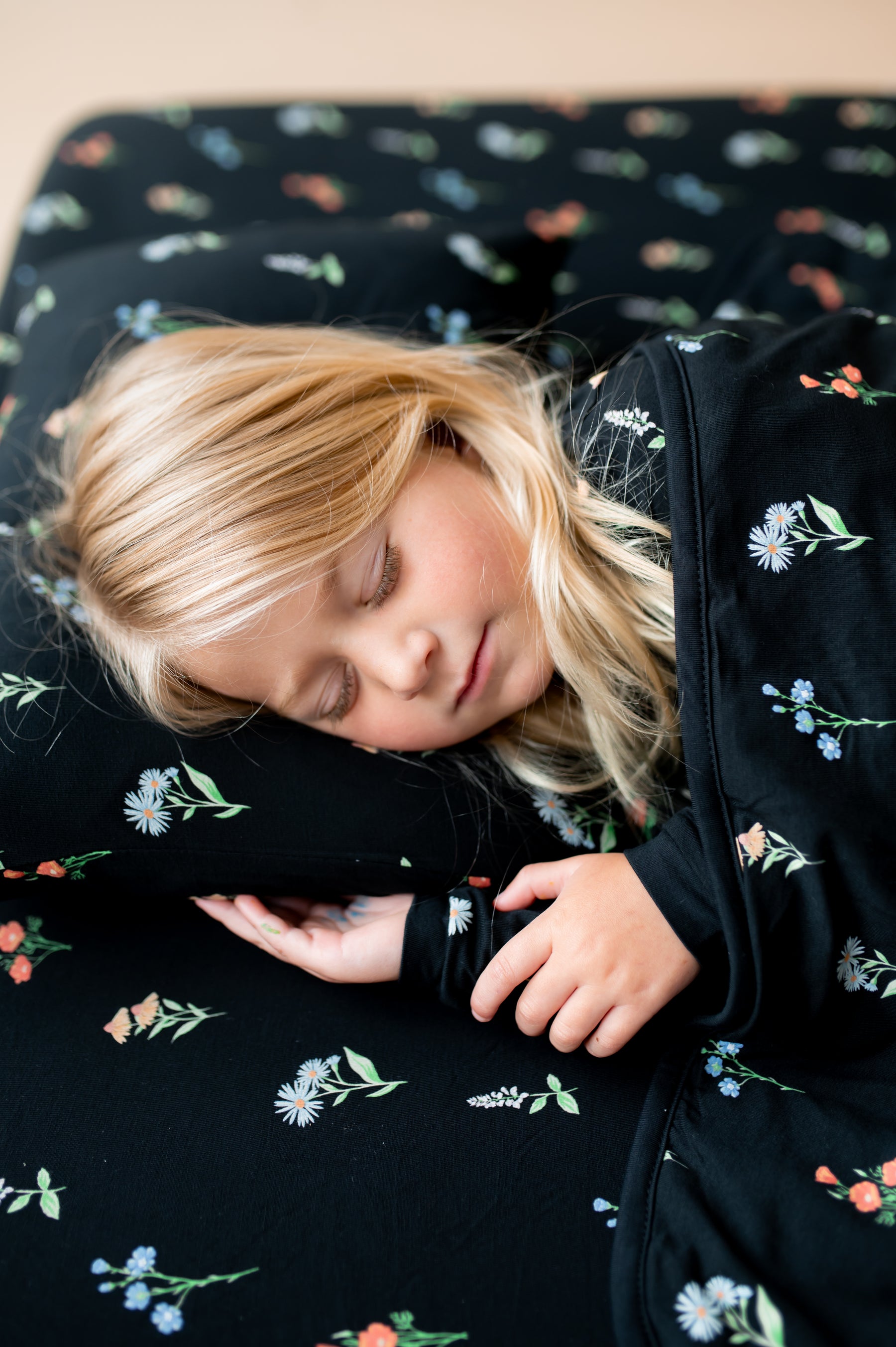 Girl sleeping on Toddler Pillowcase in Midnight Wildflower print covered under similar print Toddler blanket and sheets