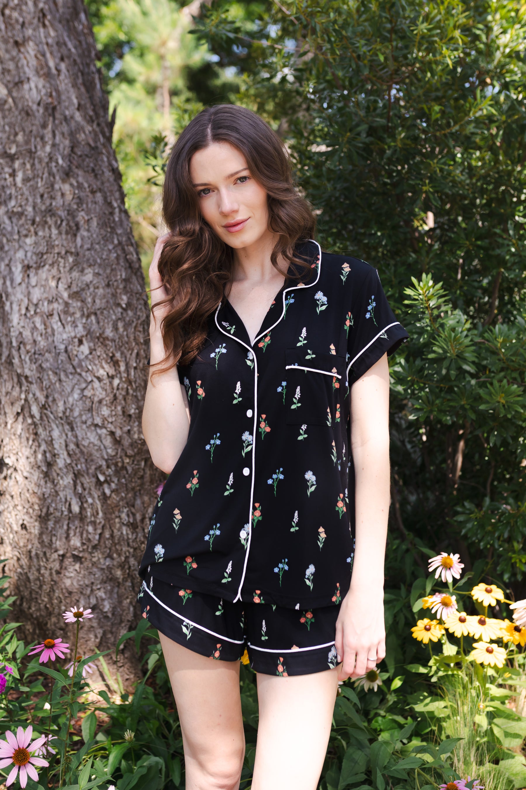 Woman wearing a black short sleeve pajama set with wildflower pattern standing outdoors