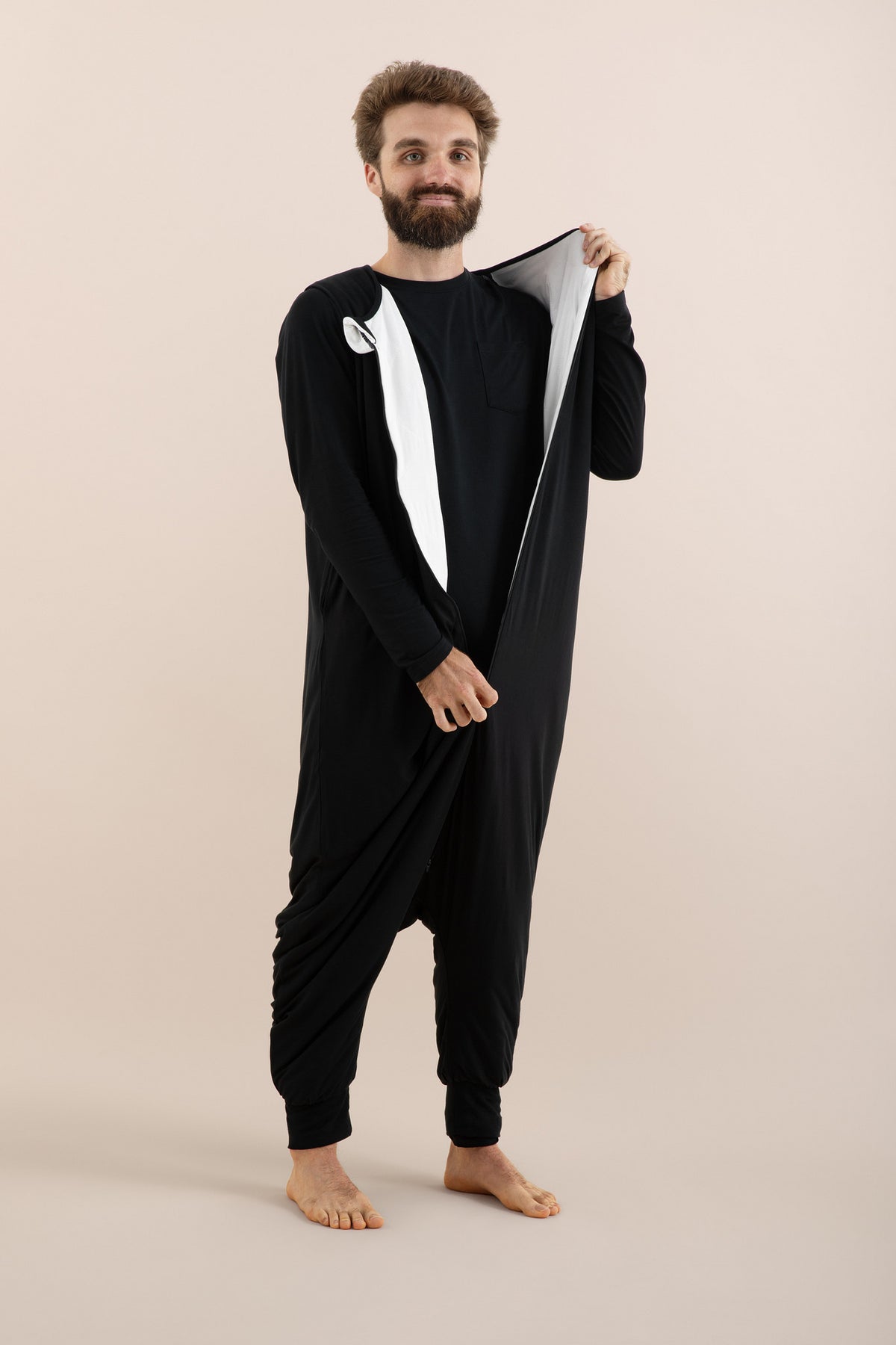 Male model wearing the Adult Sleep Bag Walker in Midnight unzipping it