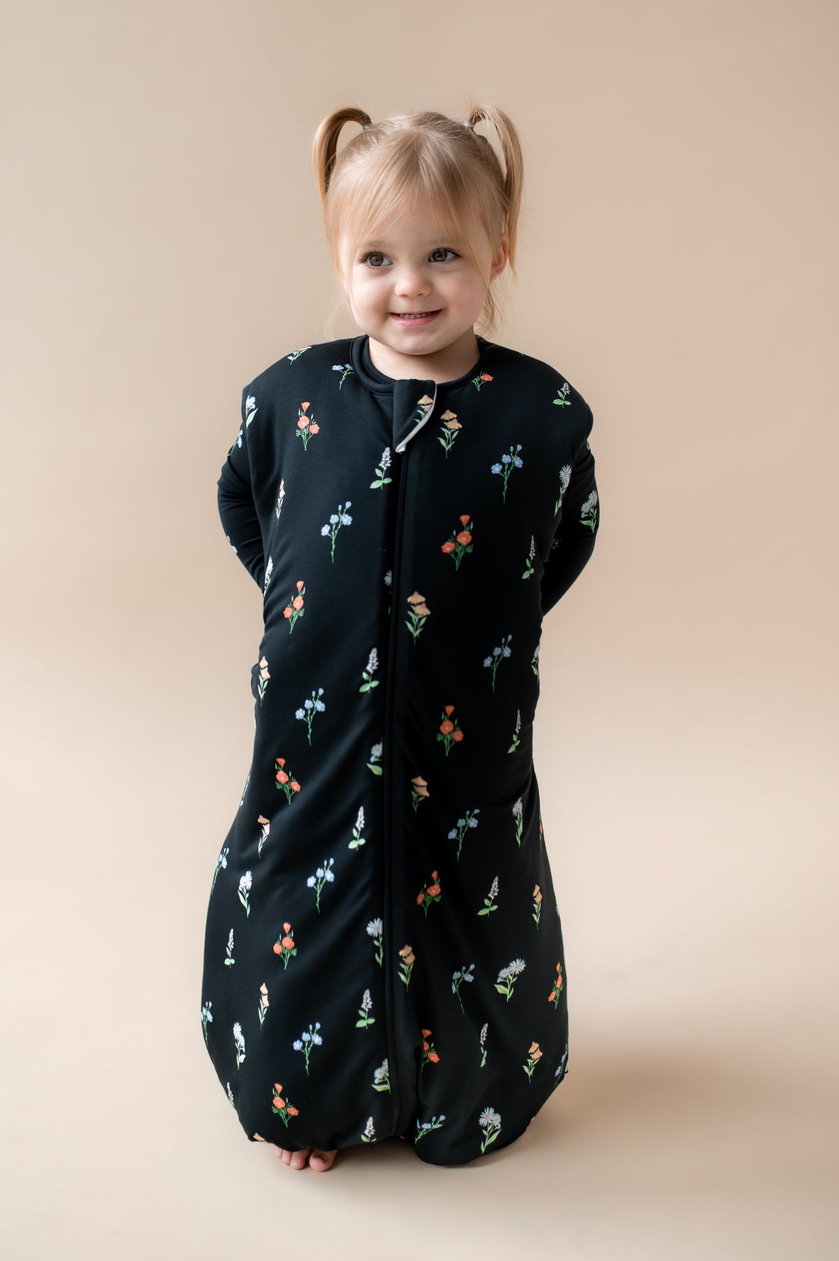 Girl wearing Sleep Bag Walker in Midnight Wildflower 2.5 print on a beige background