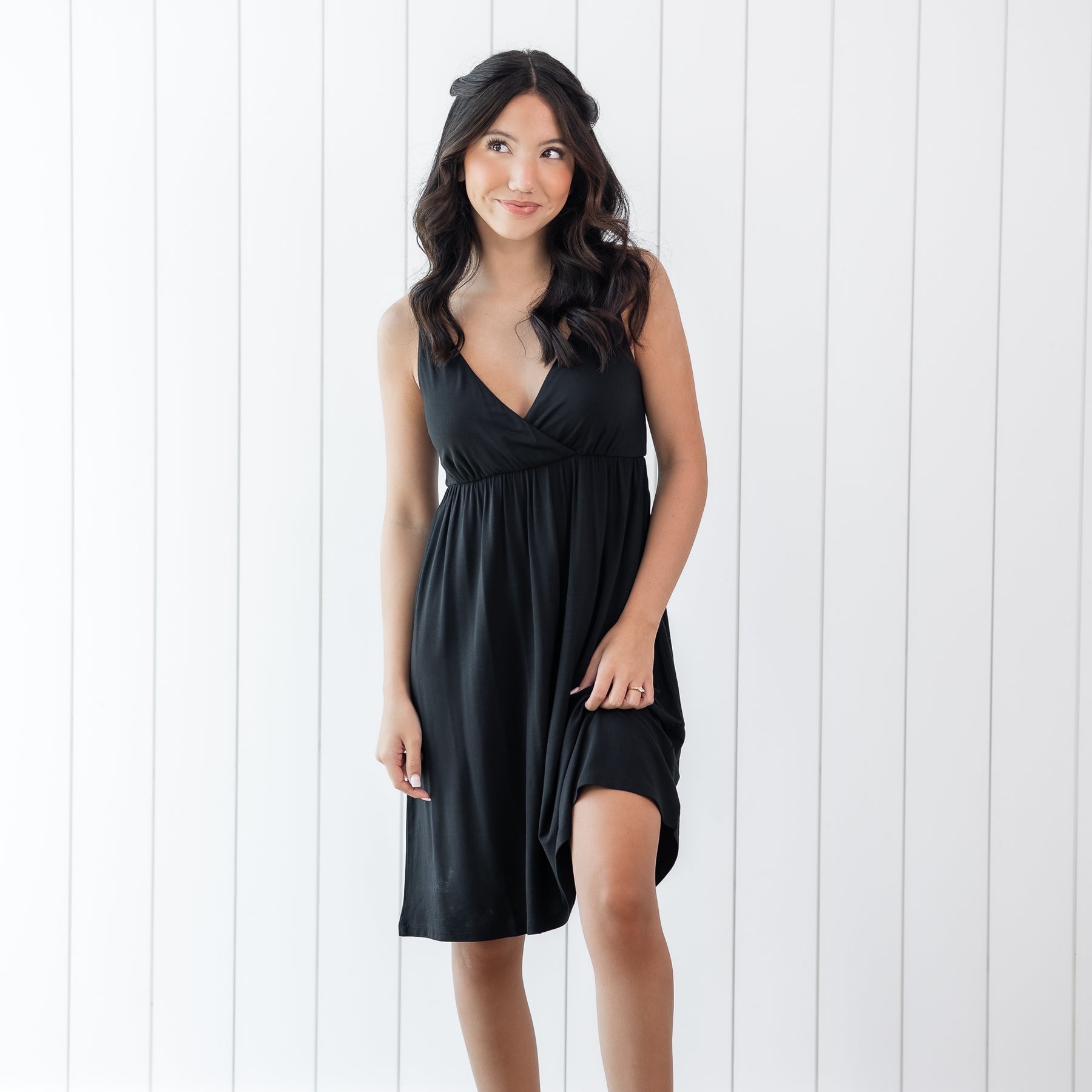 Woman wearing a black nightgown against a white wooden panel background