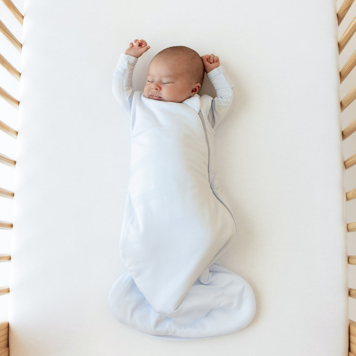 Baby sleeping without the swaddling band of the Kyte Baby Sleep Bag Swaddler in Mist 1.0