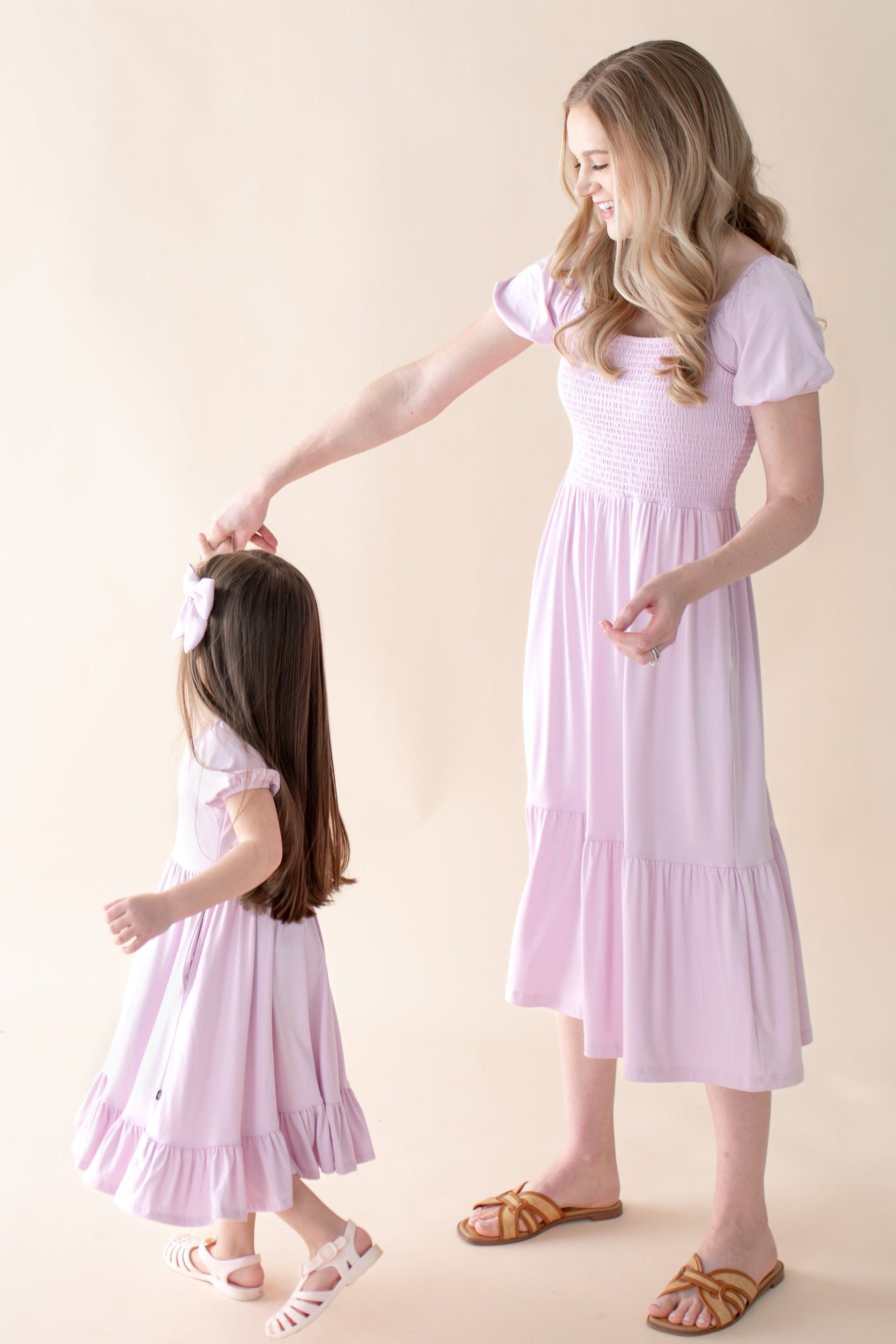 Mom and daughter wearing matching light purple dresses twirling 