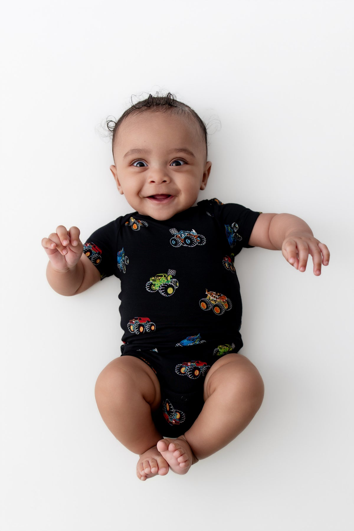 Baby smiling in Black Bodysuit in Monster Truck print on white background