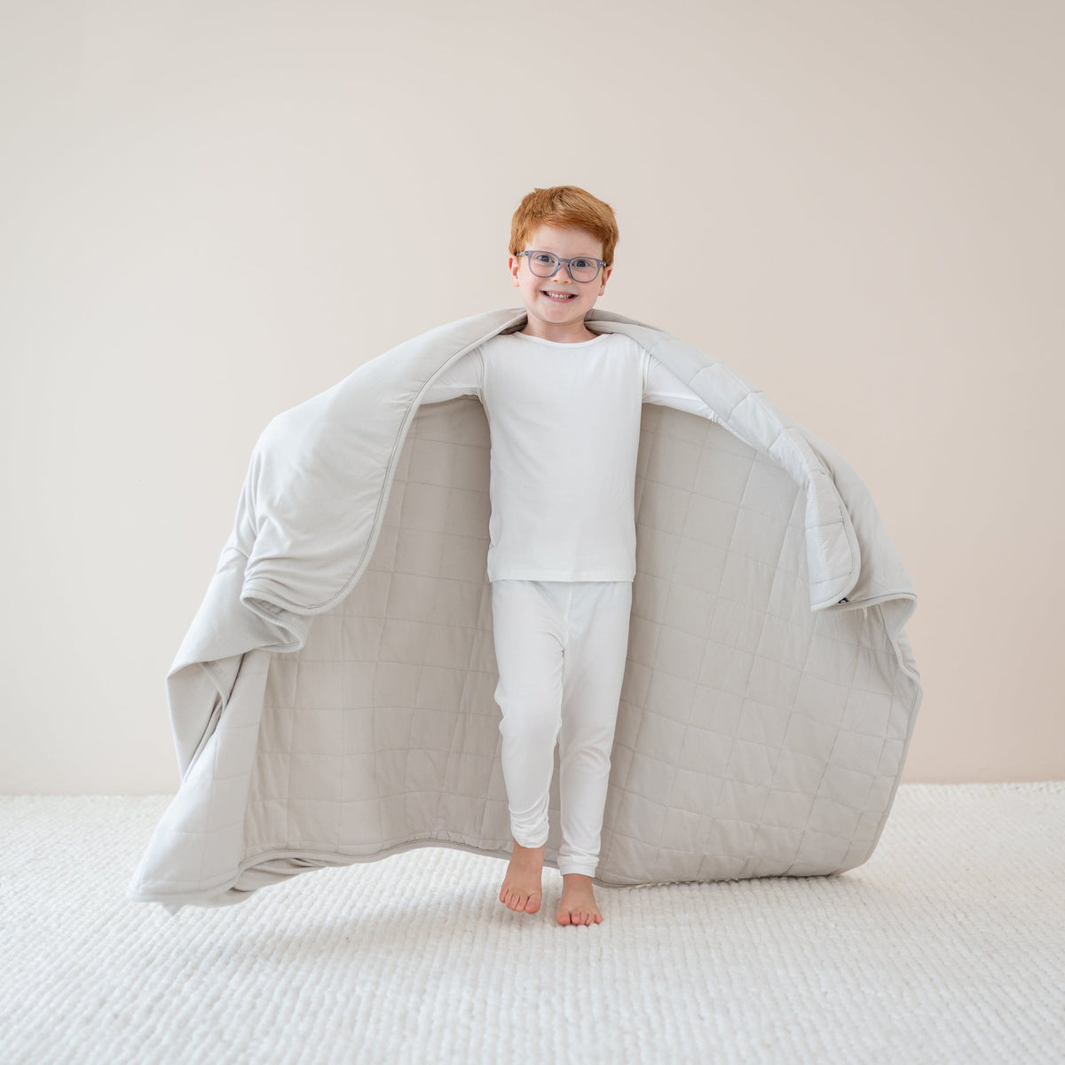 Child  in cloud pajamas holding out in Youth Blanket in Oat 1.0