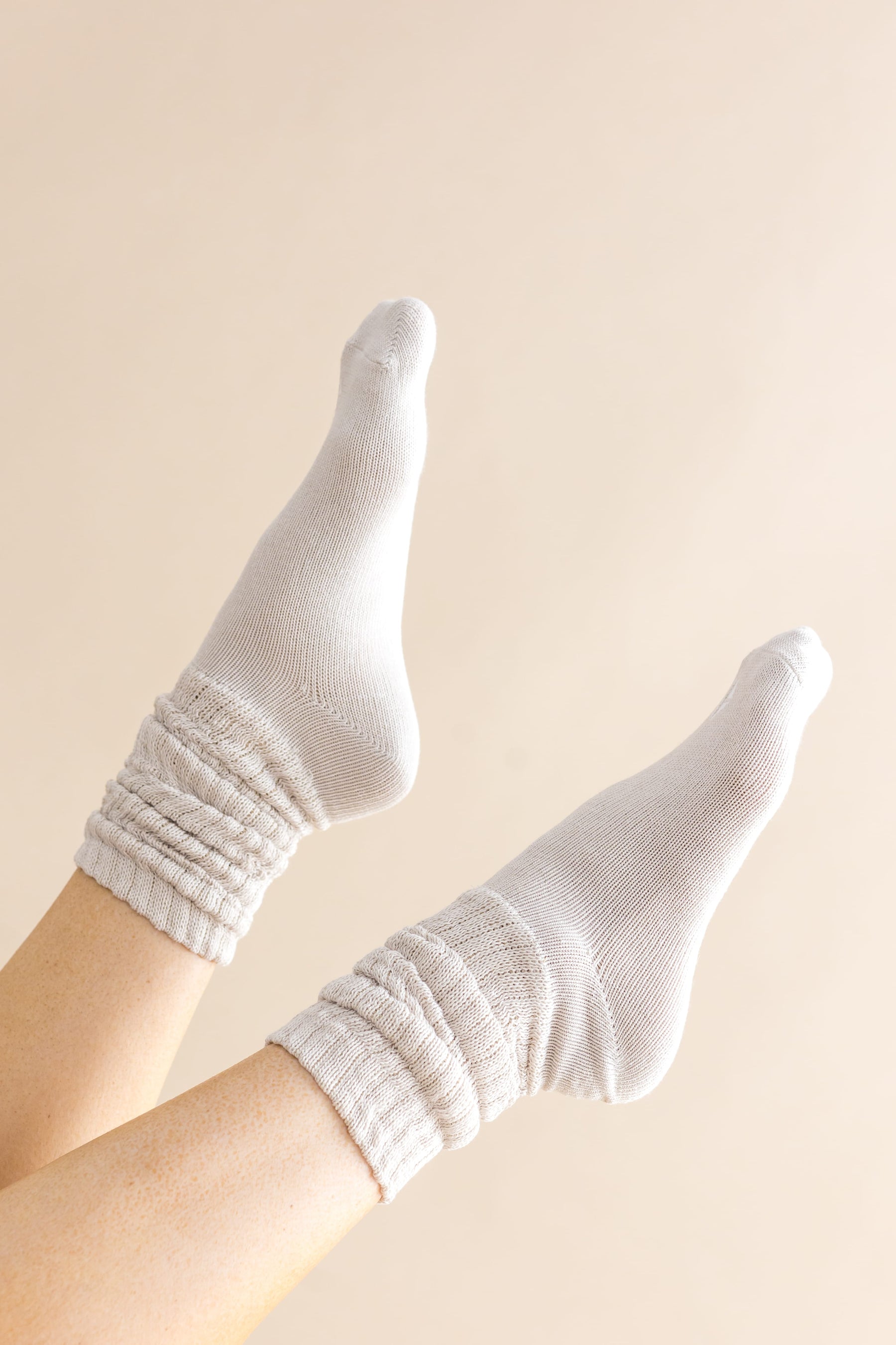 Adult Scrunch Socks in Oat shown on a models feet in the air in front of a cream colored background