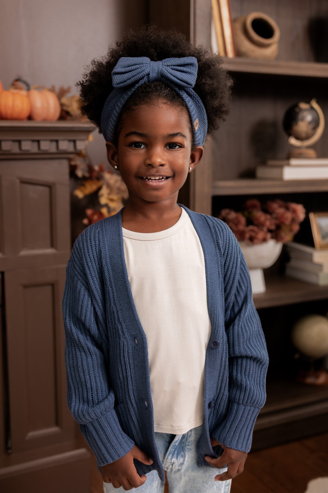 Modal standing in a living room wearing Chunky Knit Bow Headband in Oxford over white T-shirt and Chunky knit oversized cardigan in Oxford