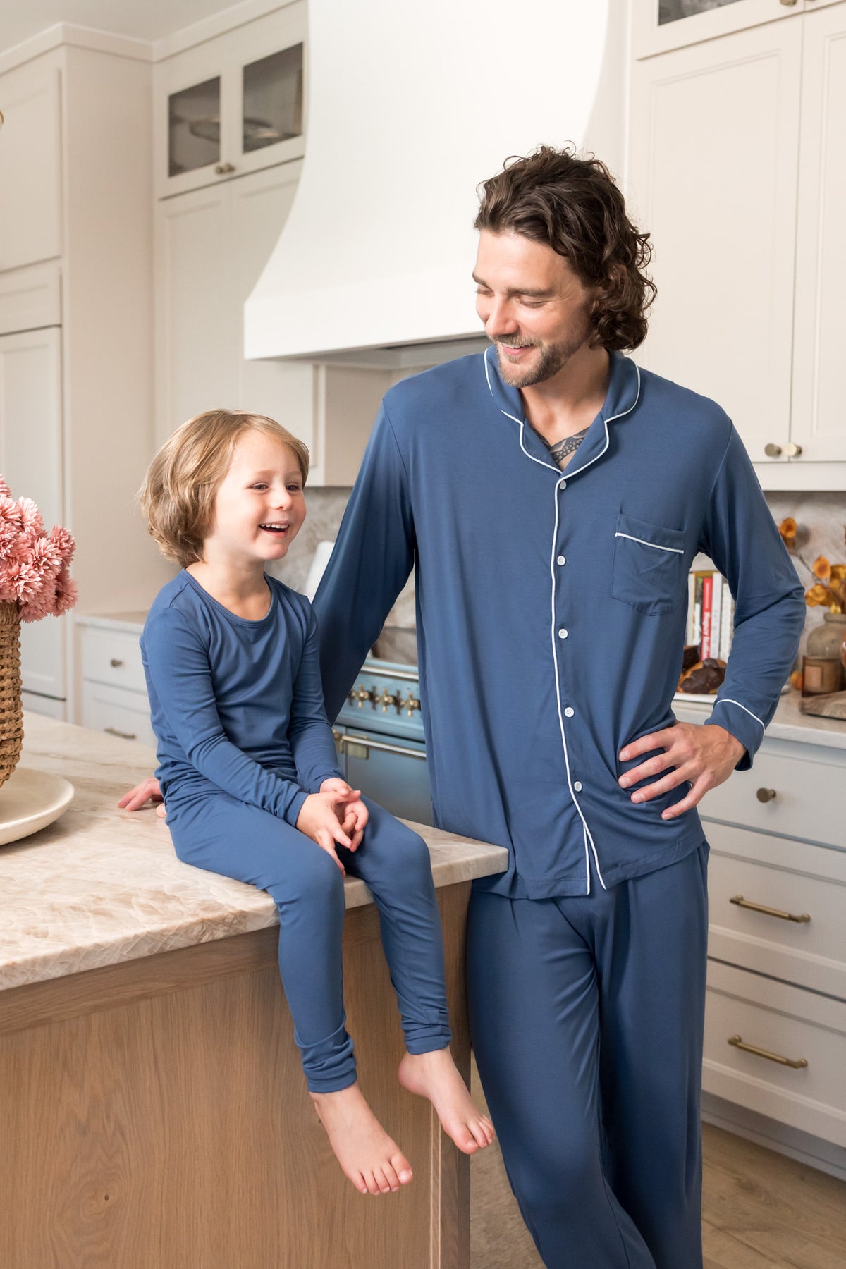 Man and child wearing matching blue long sleeve pajamas in a kitchen