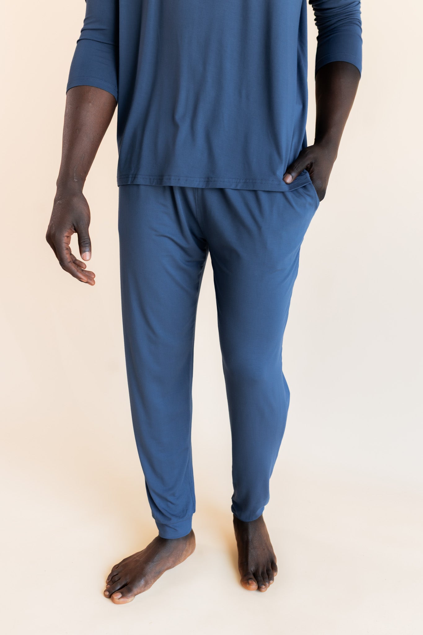 Model showcasing pockets on Men's Jogger Set in Oxford on a beige background