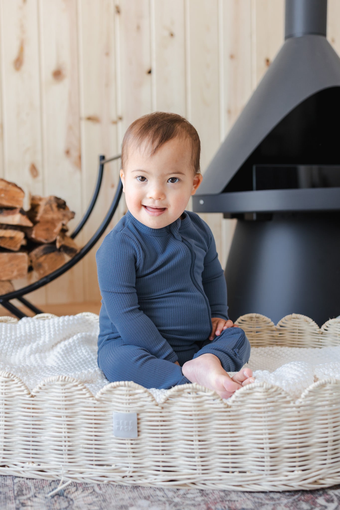 Baby sitting on a basket wearing Ribbed Zipper Romper in Oxford
