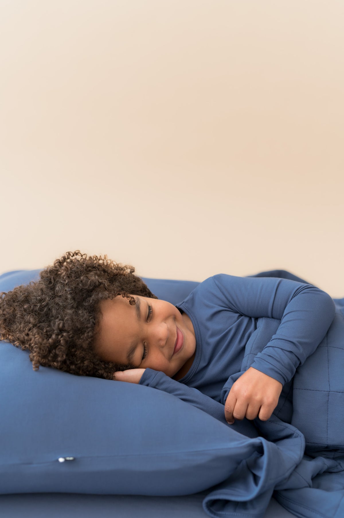Boy sleeping on Standard Pillowcase in Oxford wearing similar color shirt and covered with Oxford blanket 