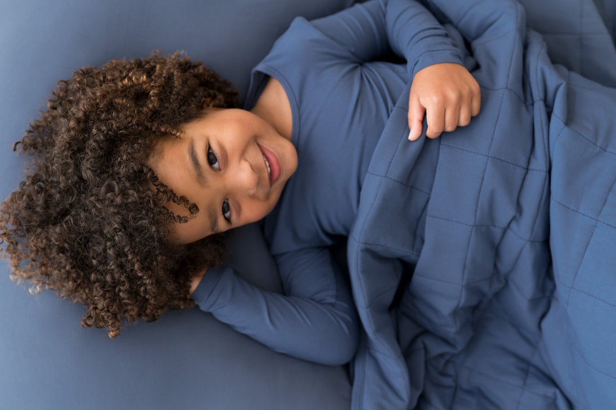 Boy lying on Standard Pillowcase in Oxford wearing similar color shirt and covered with Oxford blanket 