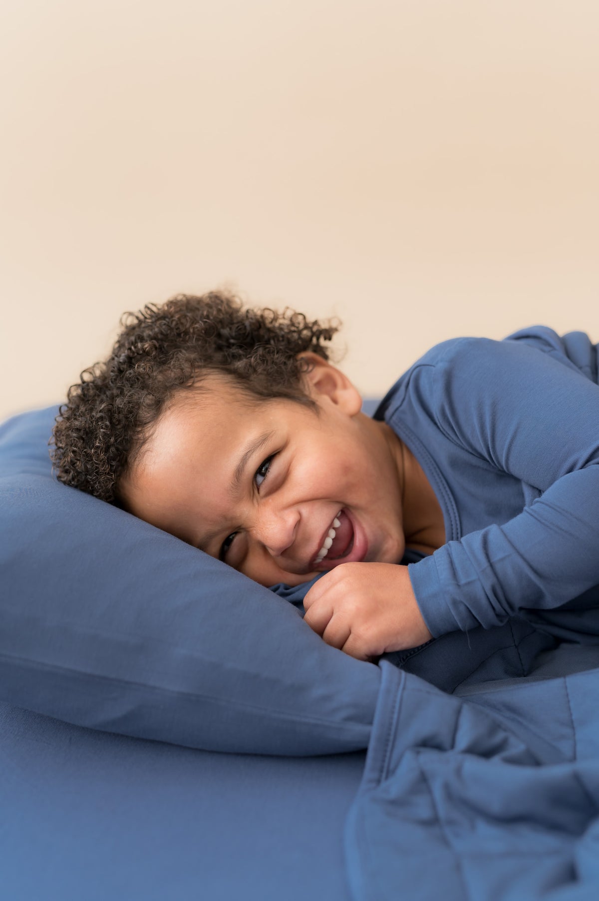 Boy lying on Toddler Pillowcase in Oxford over similar color sheets and covered with blanket in Oxford