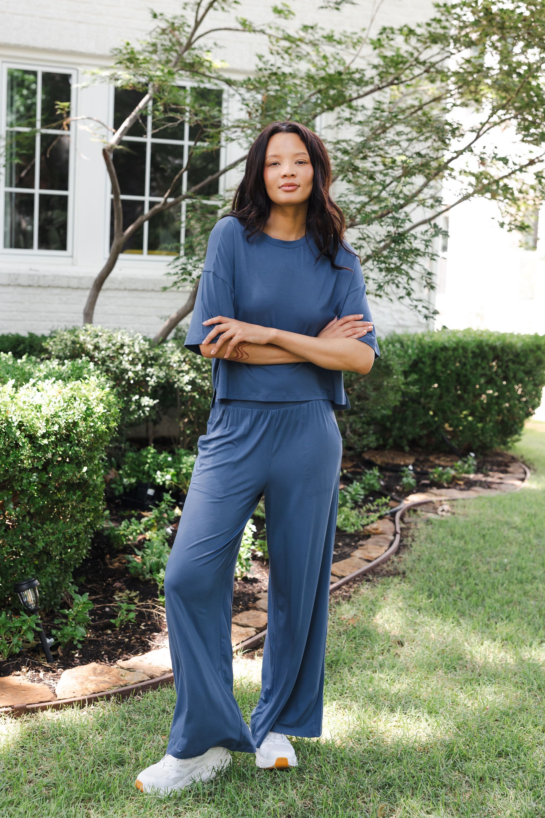 Modal wearing Women's Wide Leg Pant in Oxford standing outdoors in a garden with hands folded