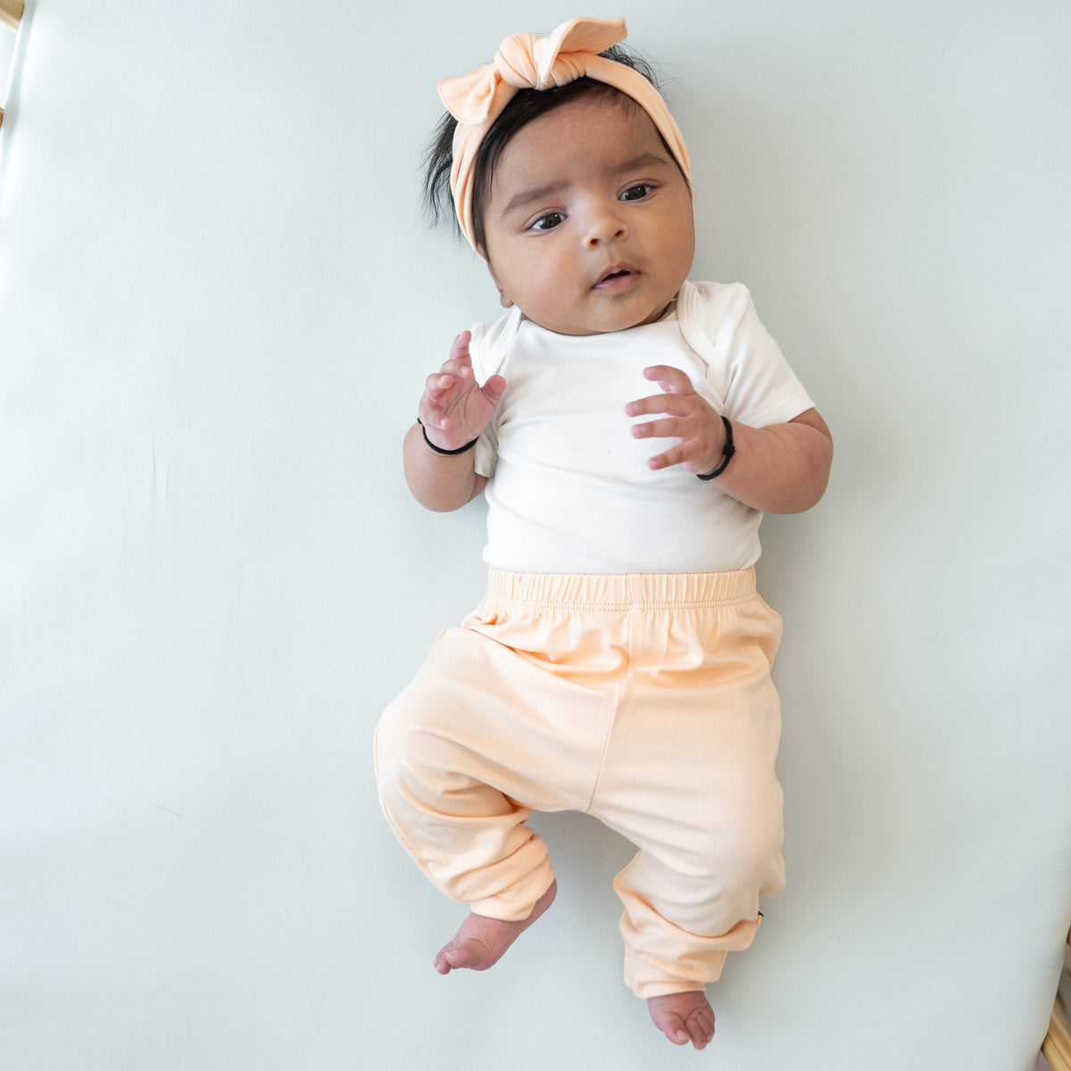 Infant model wearing the Pant in Canyon paired with a matching bow and Cloud Bodysuit