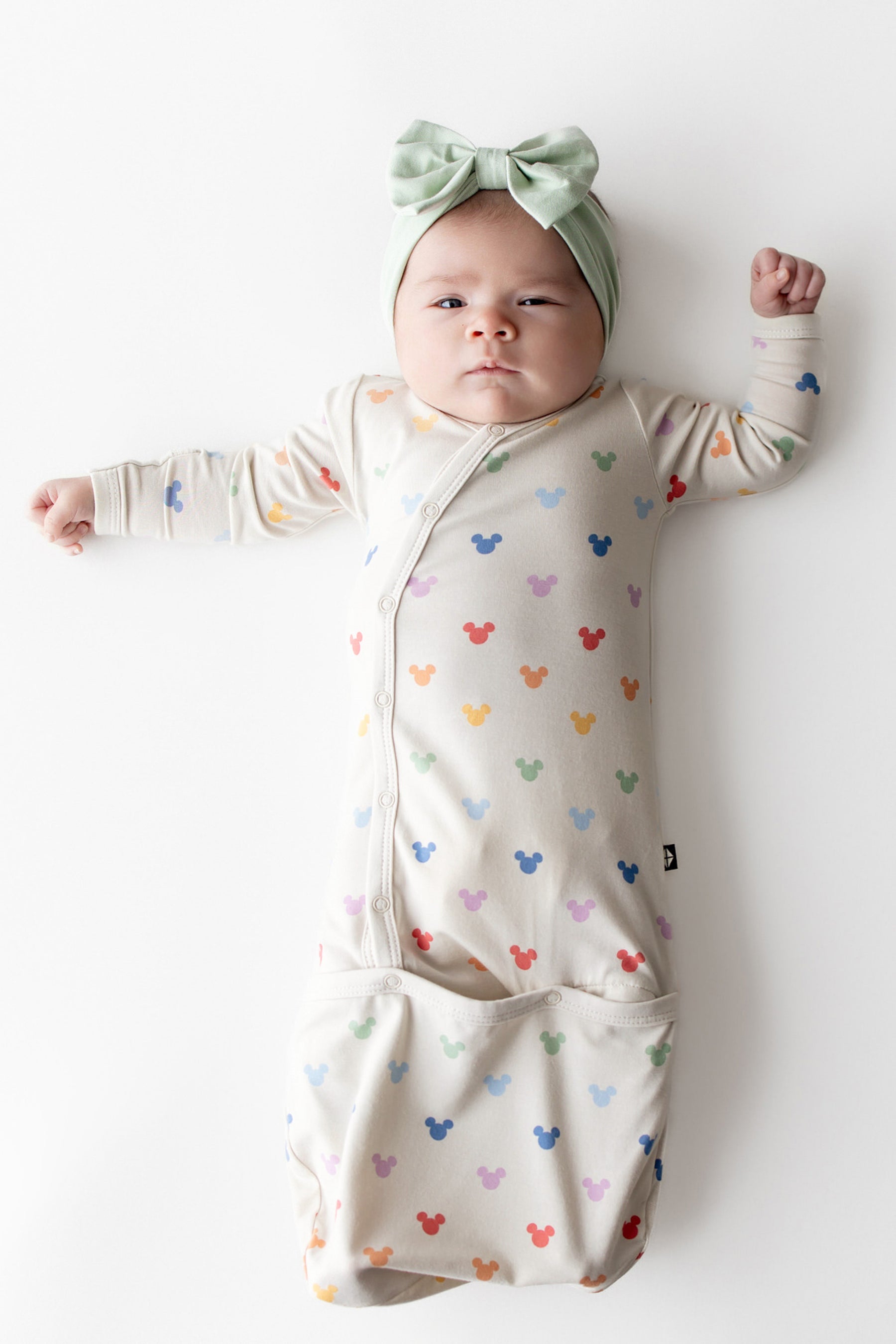 Baby in Mickey Mouse head printed bundler with button closure and light green bow 