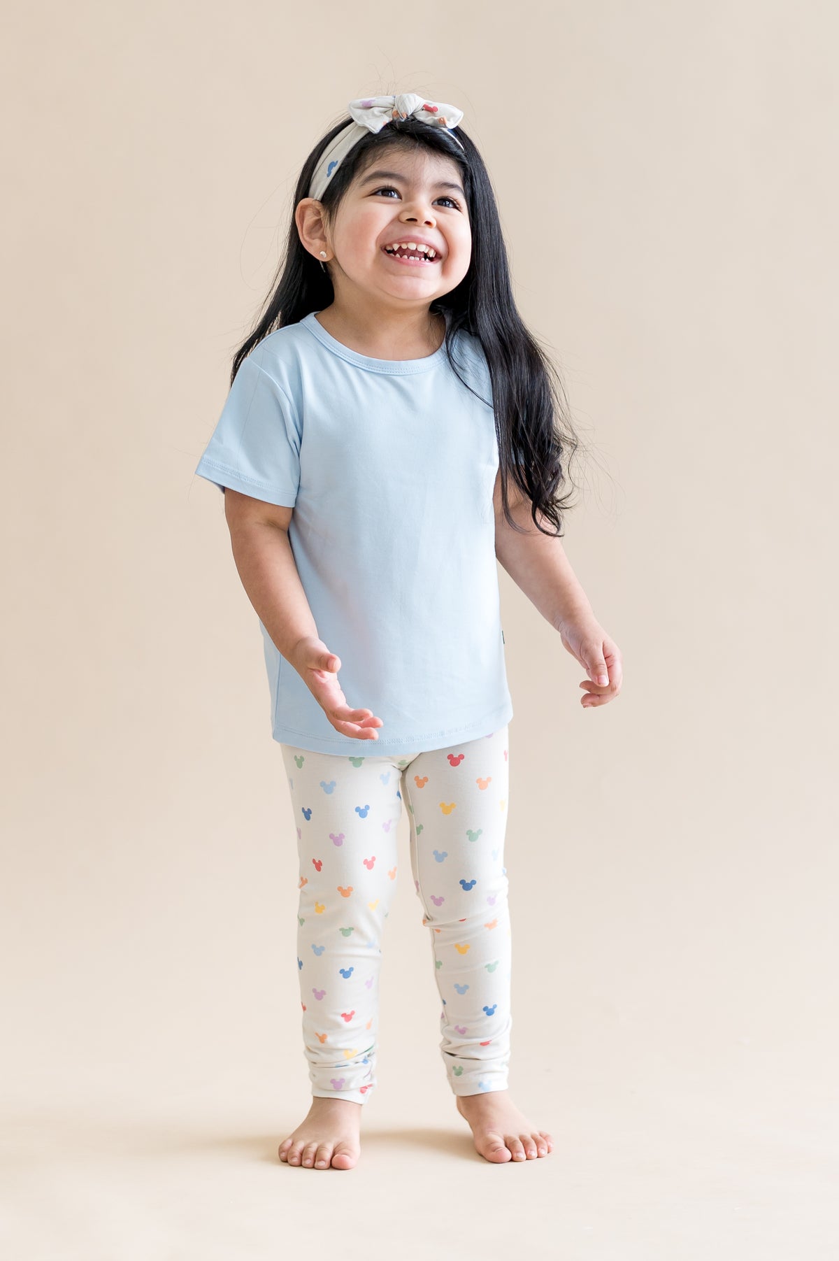 child wearing a blue tshirt with mickey mouse head patterned leggings 