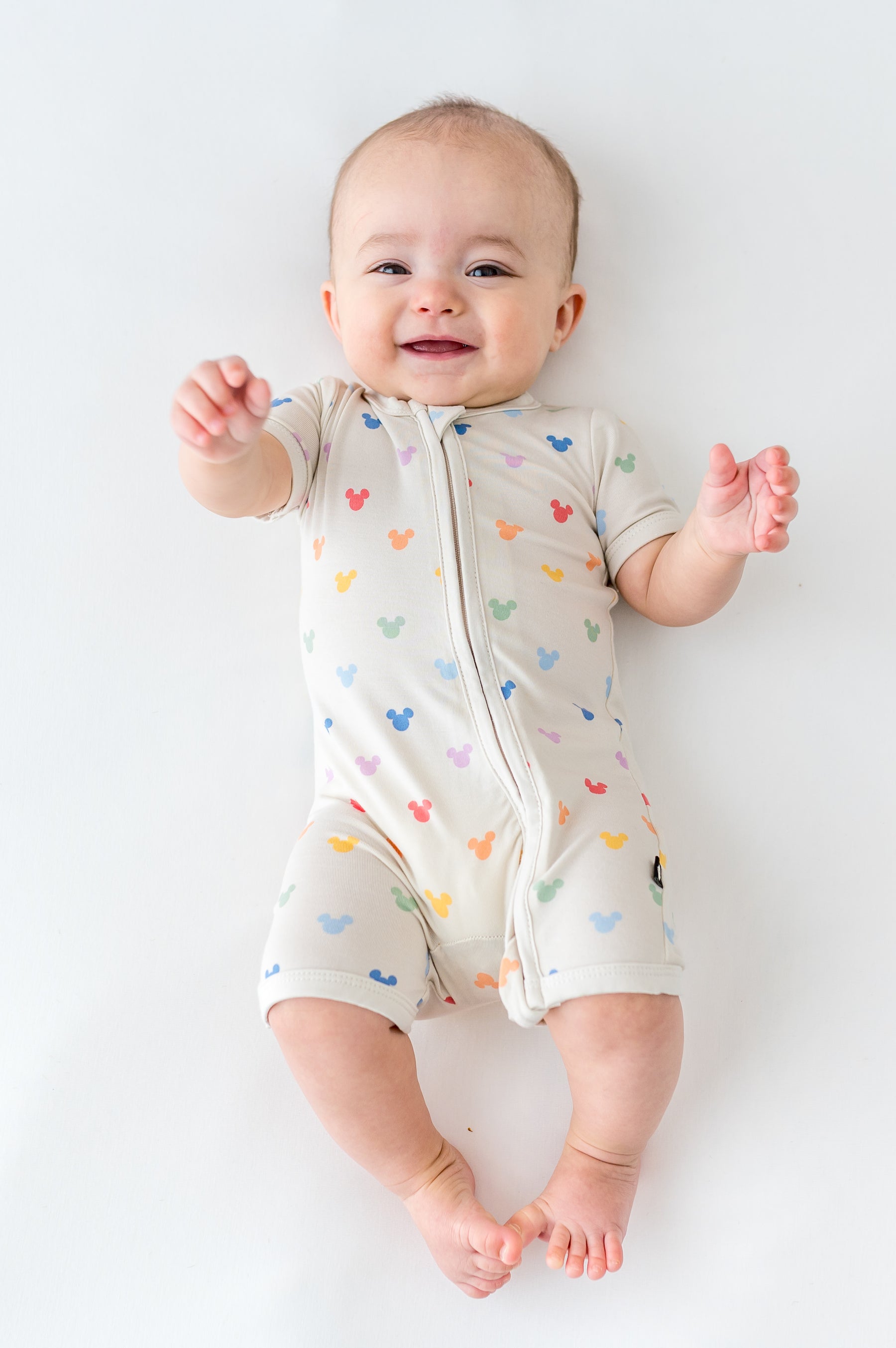 Baby wearing a pastel mickey head patterned shortall romper