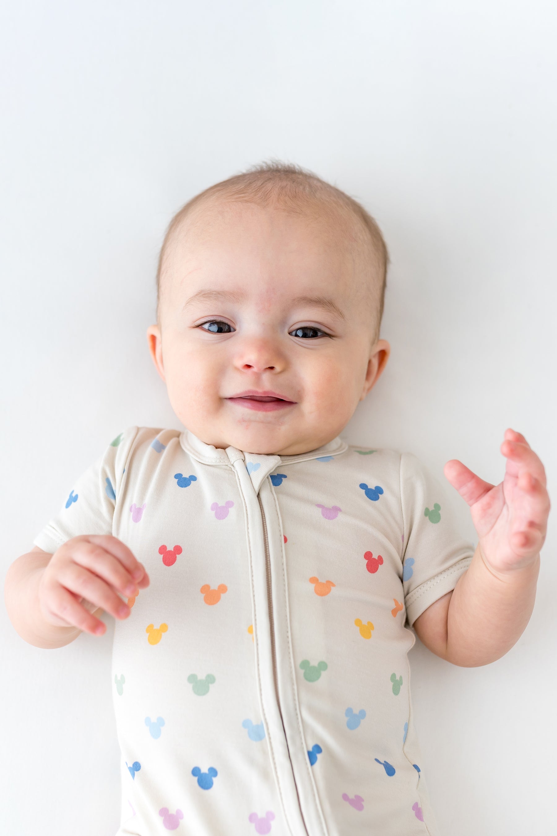baby in a short sleeve style romper with a zipper in a mickey head pattern