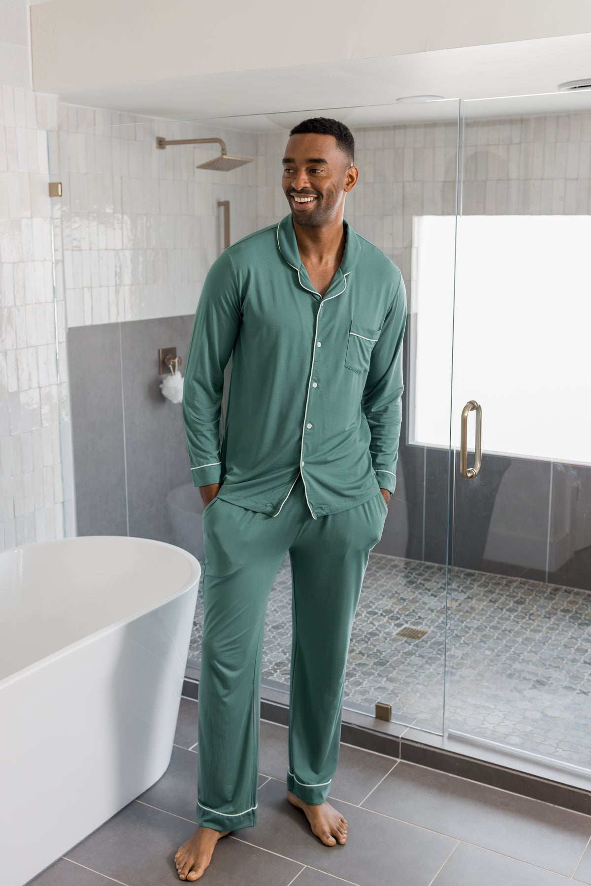 Model wearing Men's Long Sleeve Pajama Set in Pine standing in a bathroom