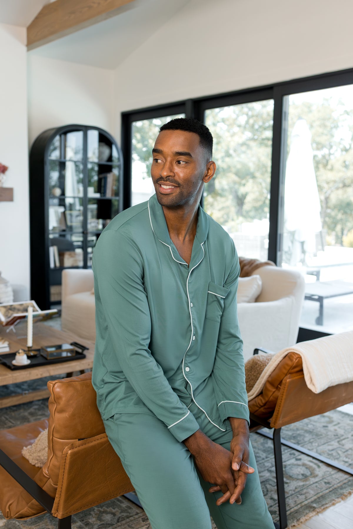 Model sitting in a living room wearing Men's Long Sleeve Pajama Set in Pine
