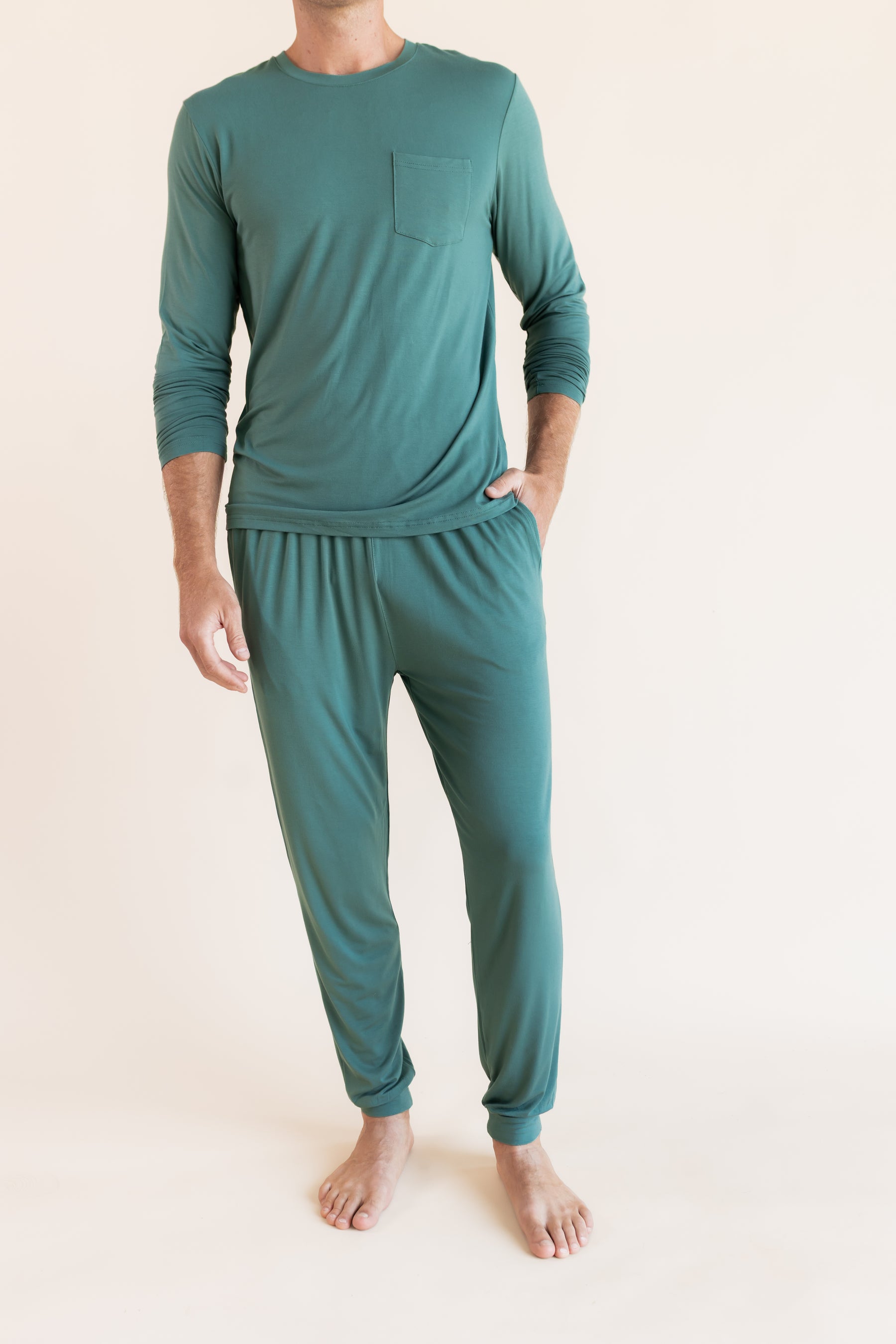 Model wearing Men's Jogger Set in Pine with pockets on a beige background