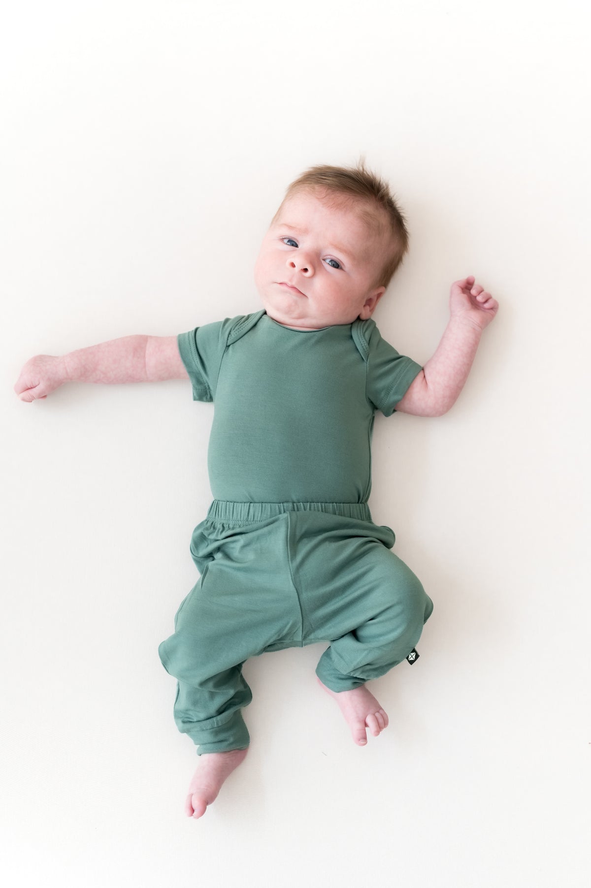 Baby wearing Pant in Pine over Pine bodysuit on a beige background