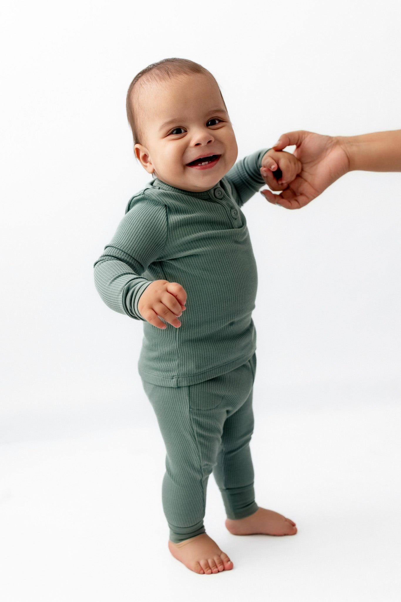 Baby holding hand wearing Ribbed Infant Henley Set in Pine on a white background